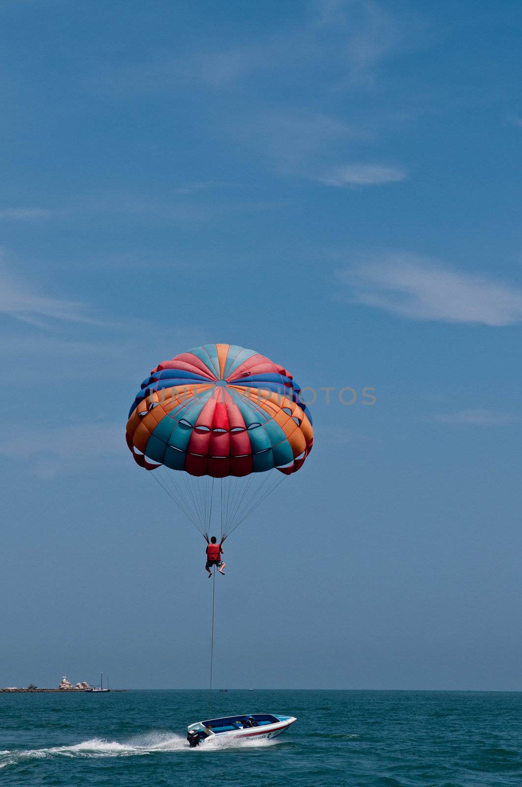 Paraglider launching from the ridge with colorful canopy against a blue sky.