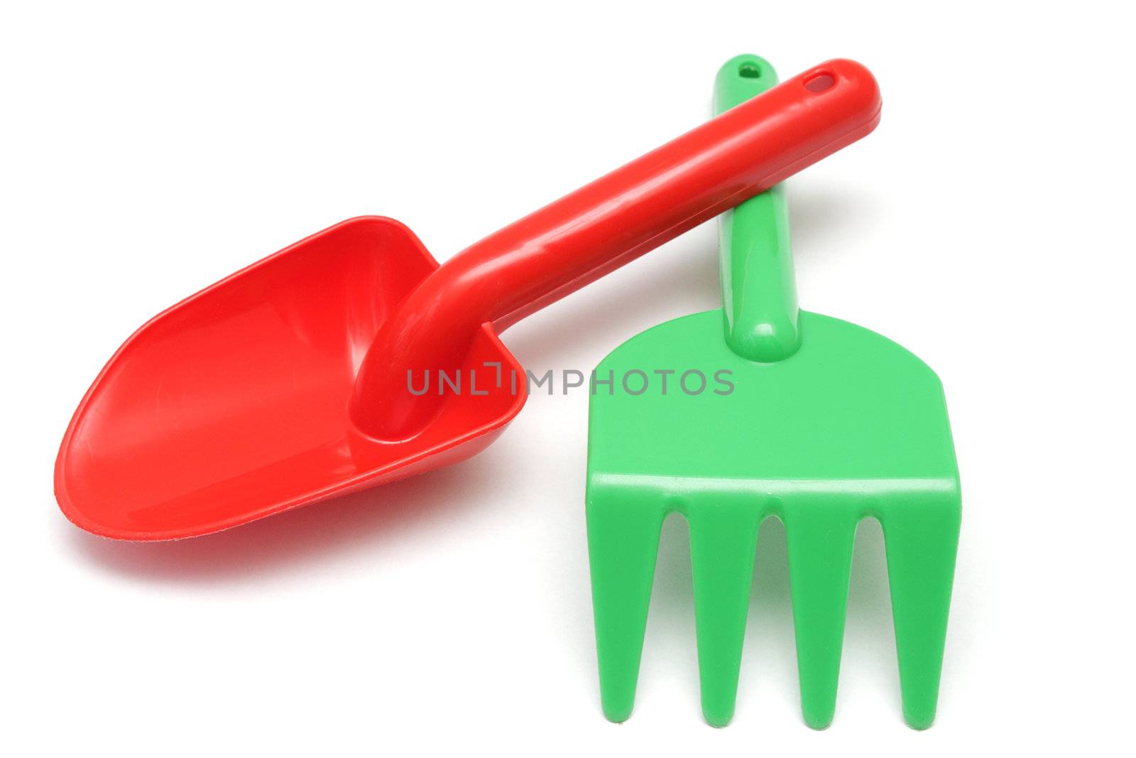 Toy red shovel and green rake isolated on white by pulen