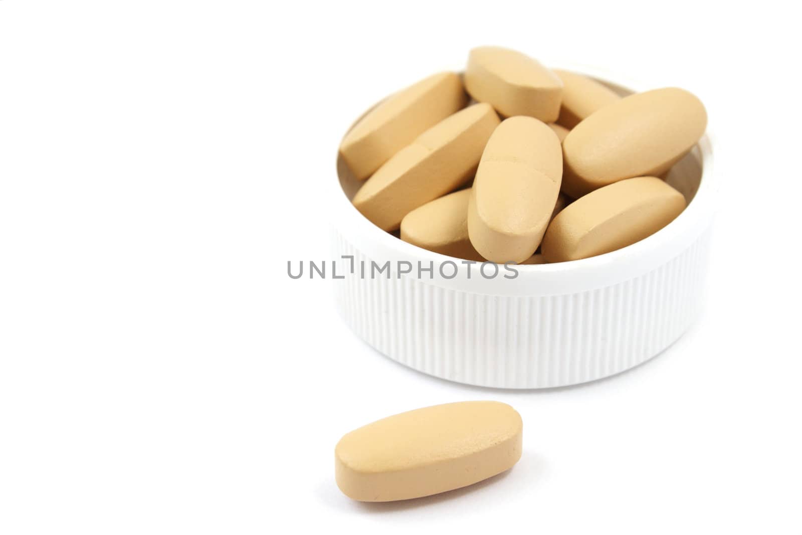 Multivitamin pills in the white plastic cap isolated on white background
