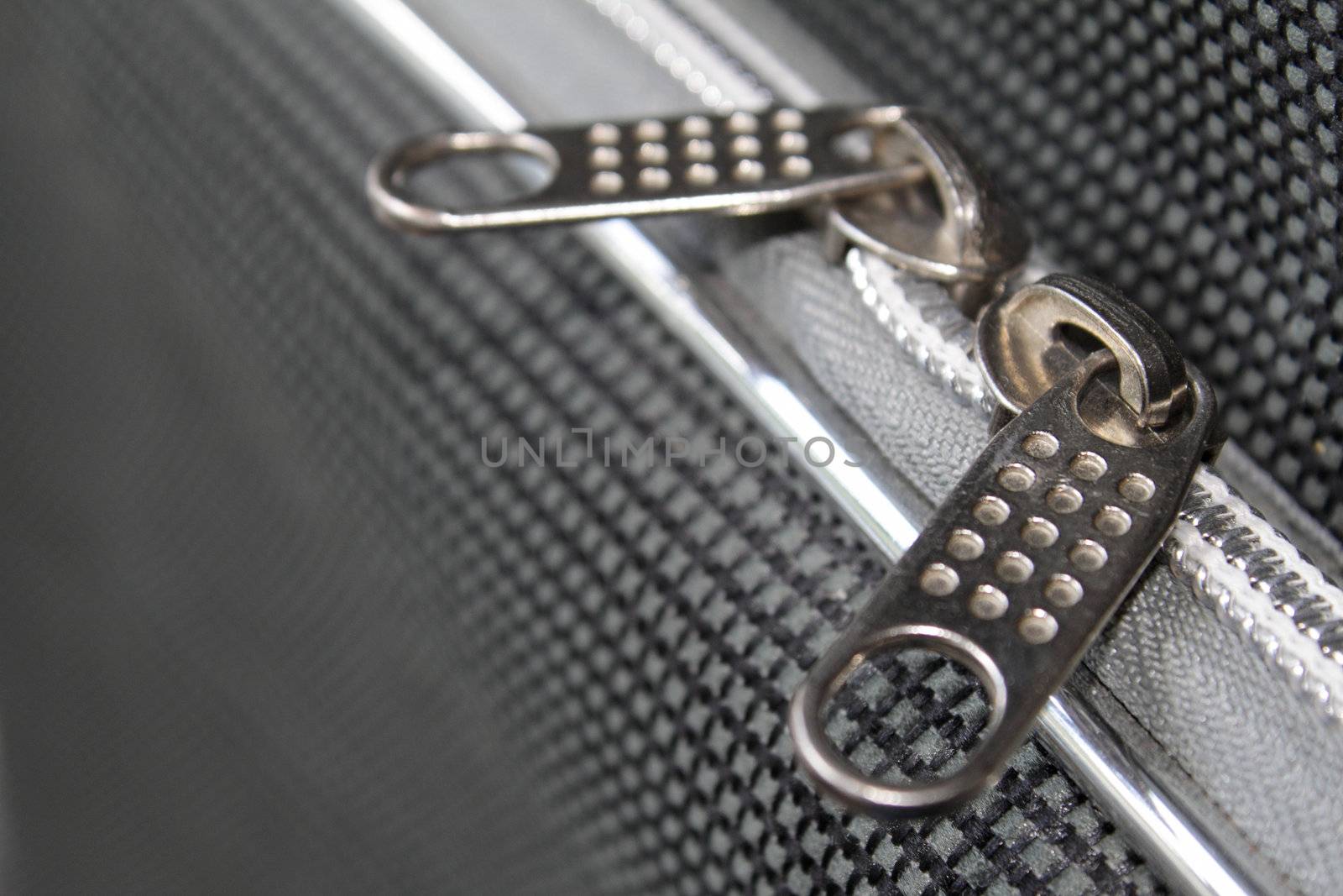 Two zipper clasps on the grayish suitcase