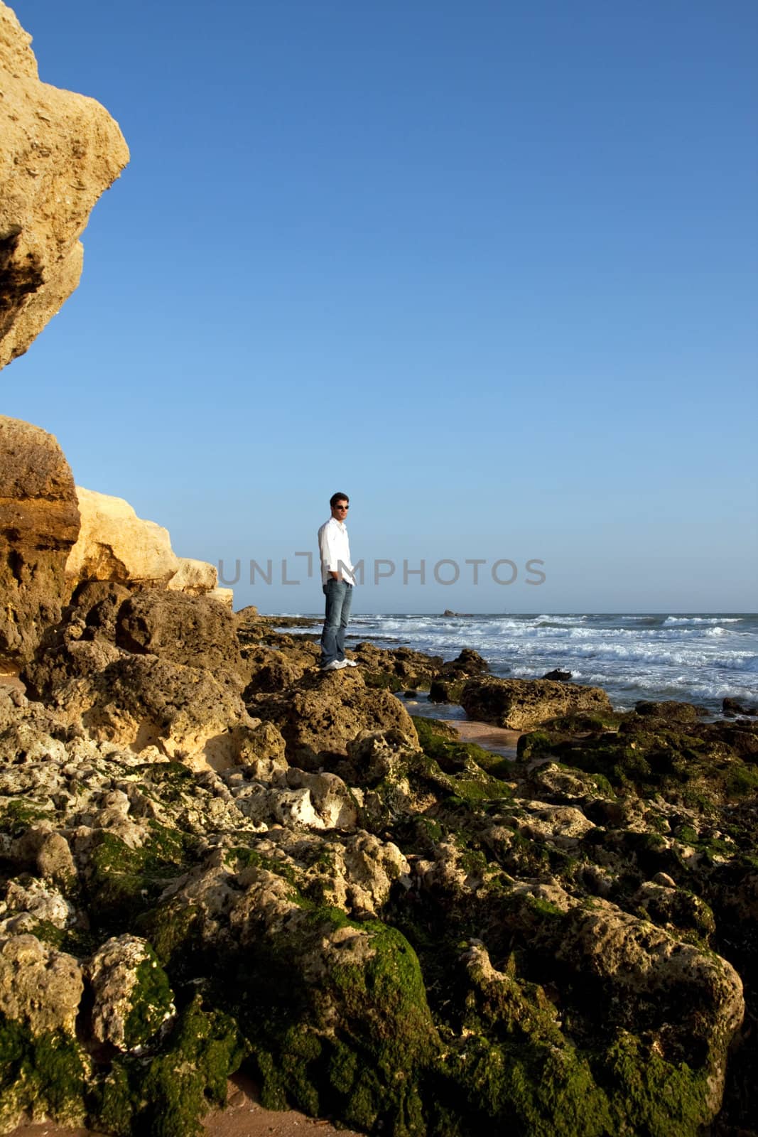 View of a young man on the shoreline enjoying the sea.