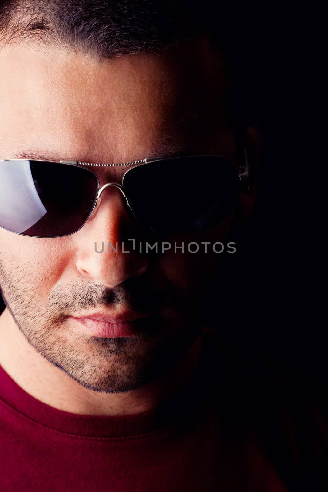 Close detail view of a young male man with dark shades  isolated on a black background.
