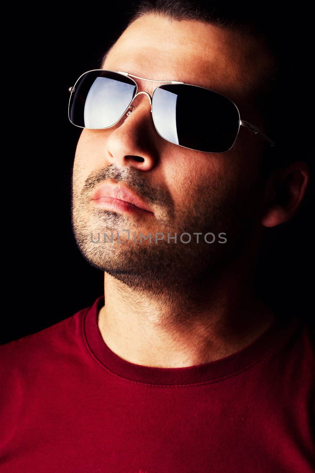 Close detail view of a young male man with dark shades  isolated on a black background.
