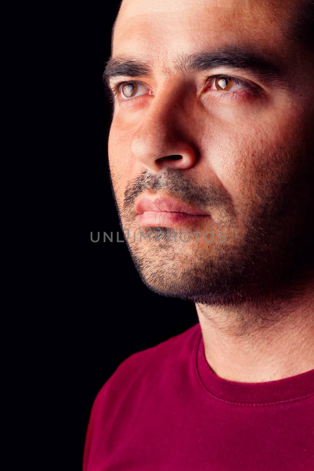 Close detail view of a young male man with a serious look isolated on a black background.