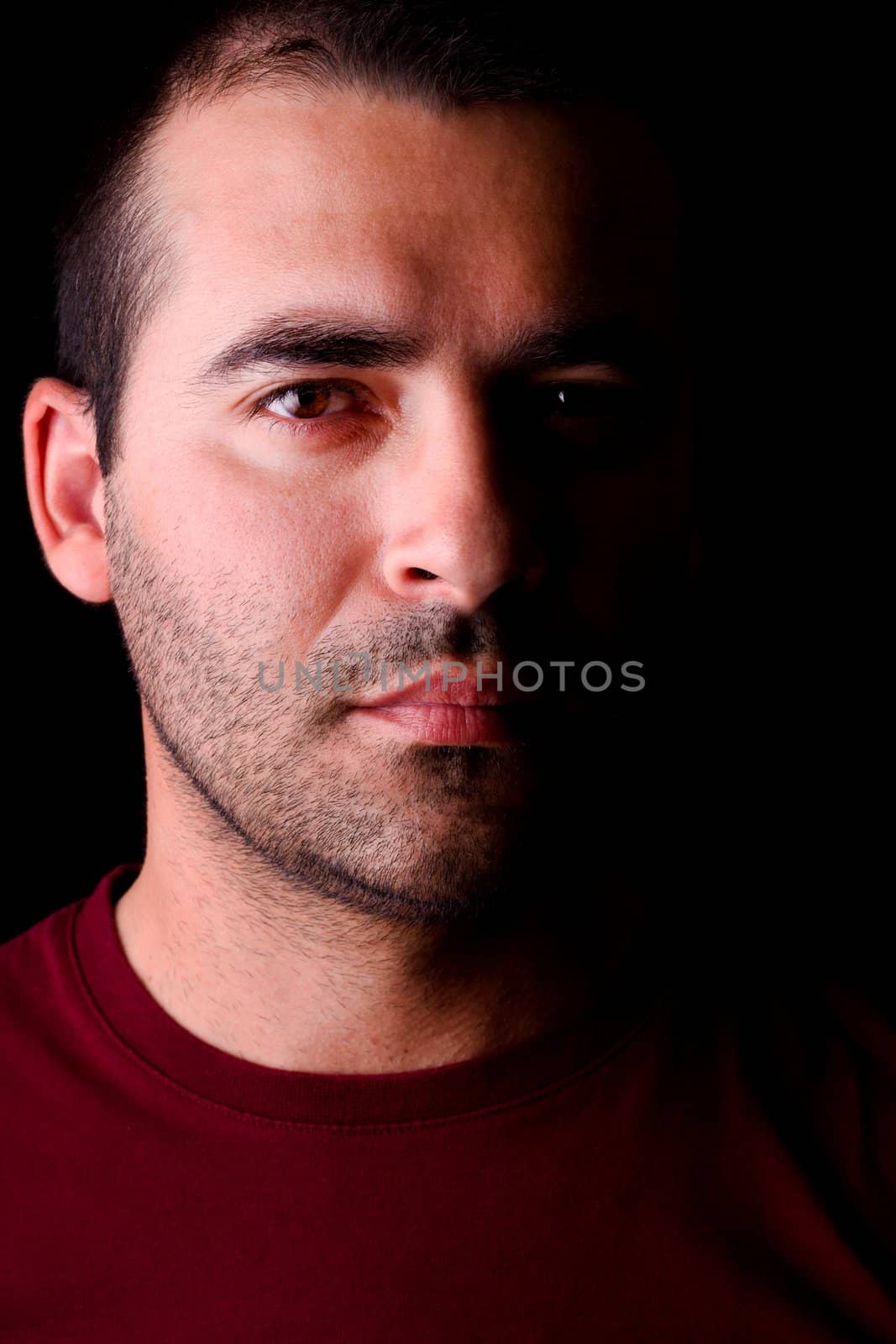 Close detail view of a young male man looking straight forward isolated on a black background.