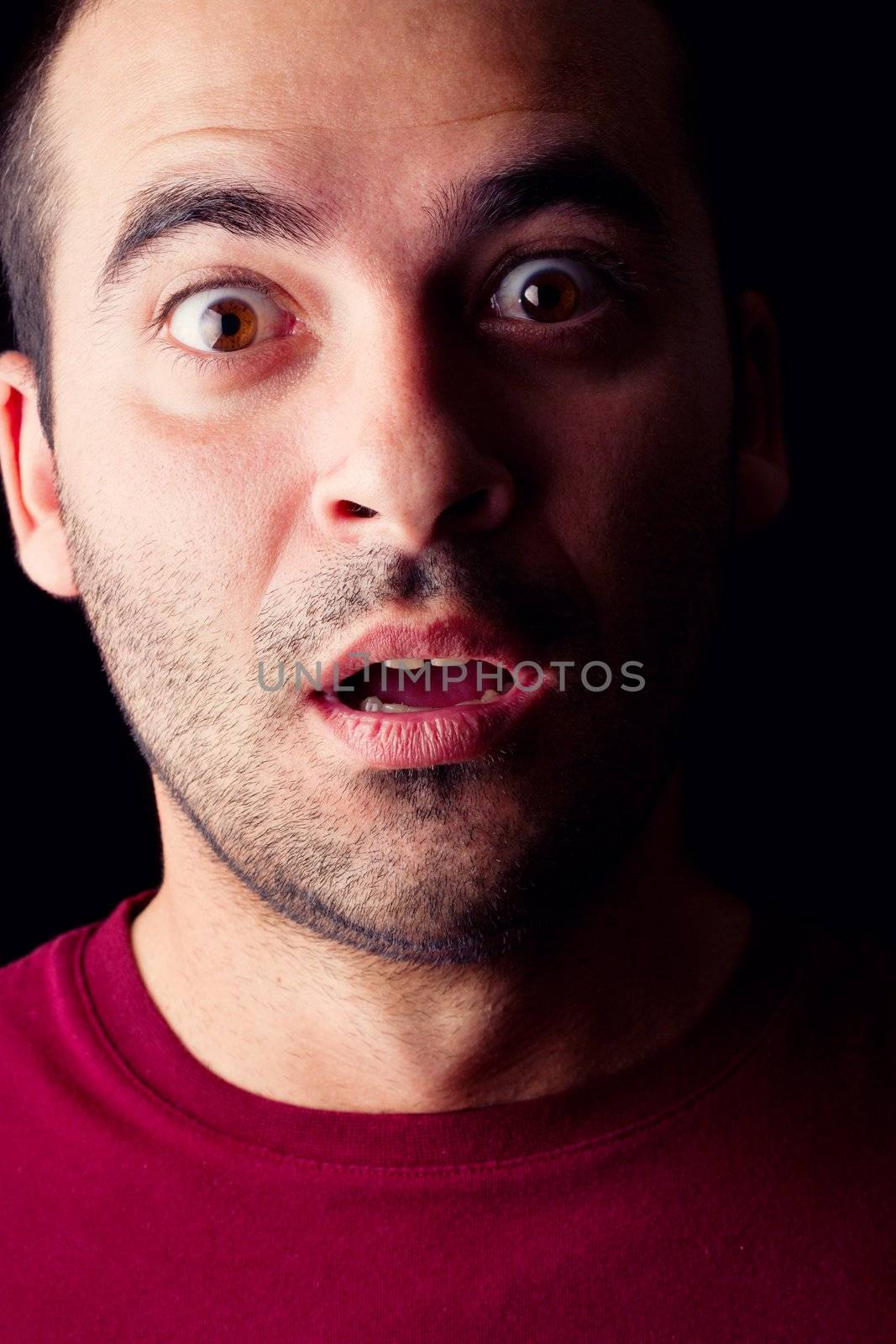 Close detail view of a surprised young male man isolated on a black background.