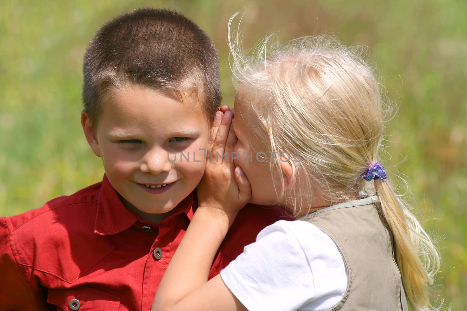 Girl whispering secret to a smiling boy