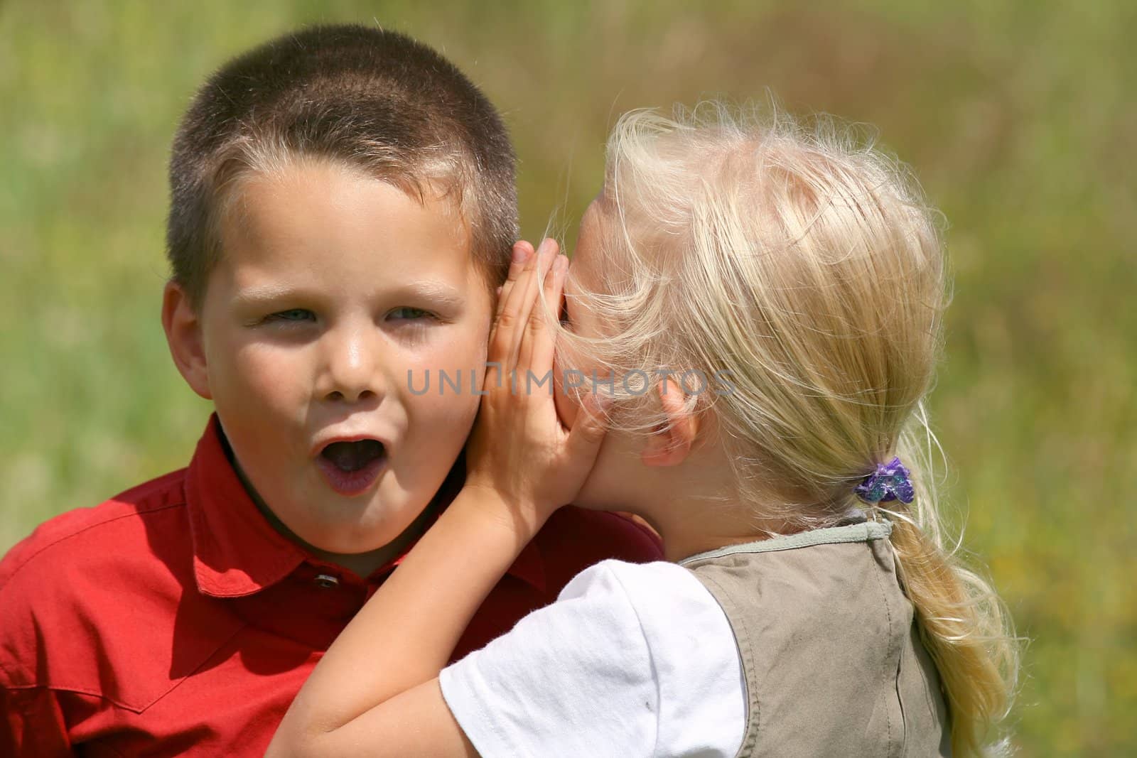 Girl whispering secret to a stunned boy