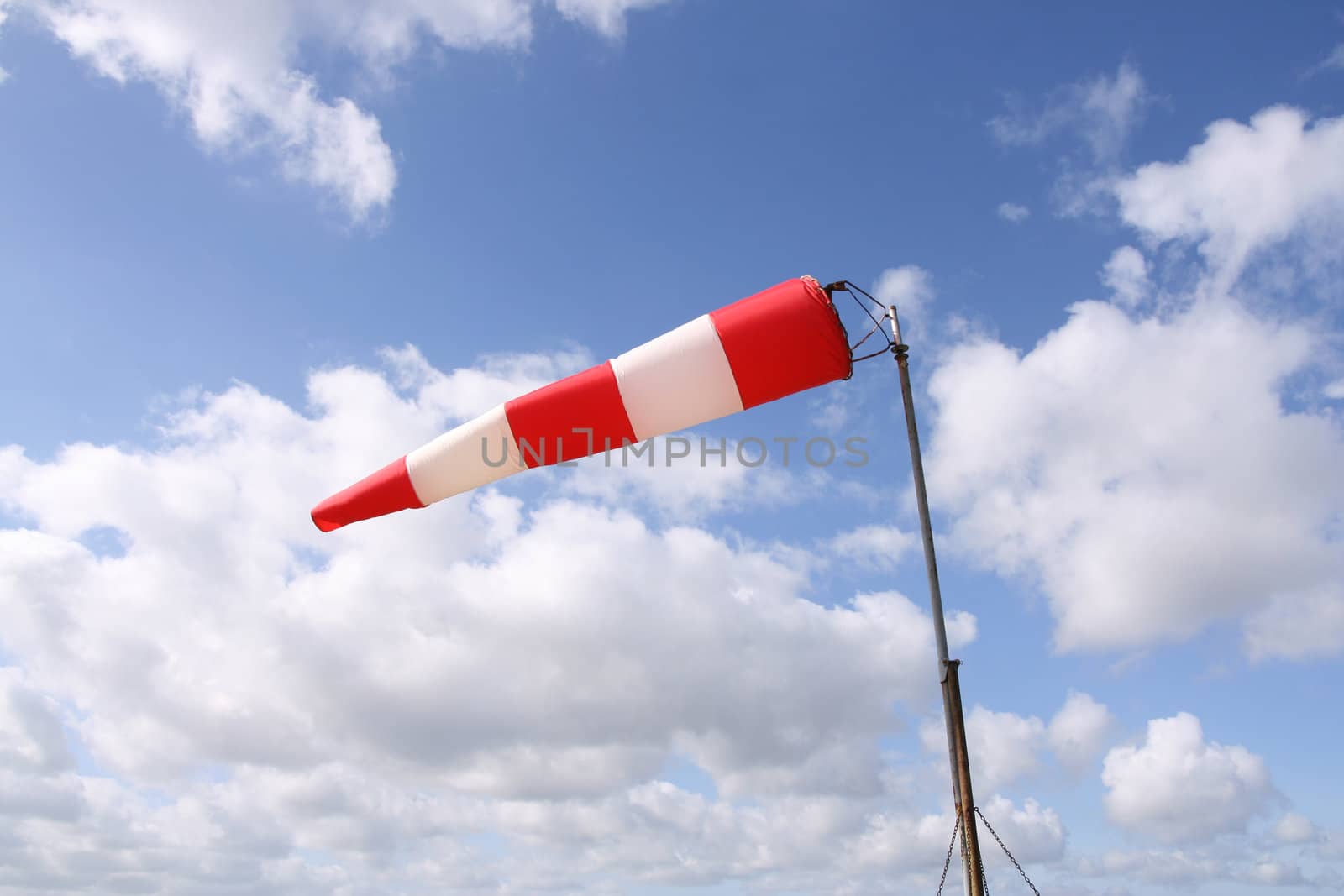 Red and white windsock blows against a blue sky