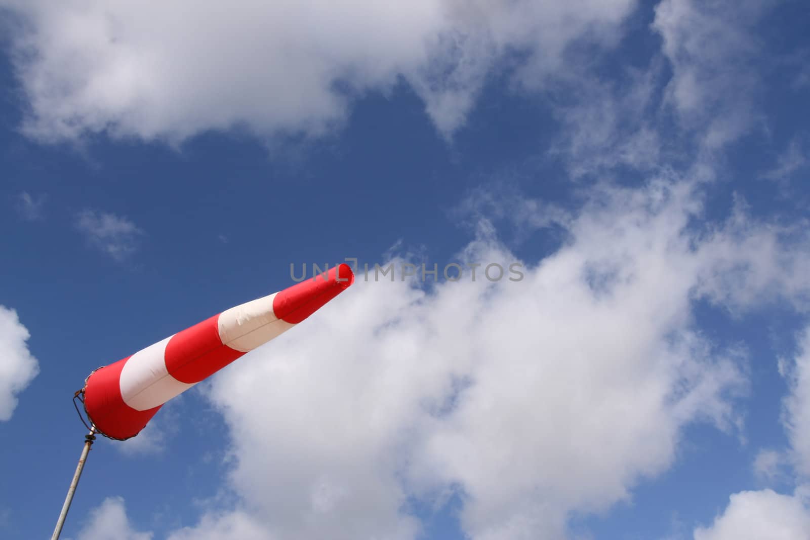 Red and white windsock blows against a blue sky