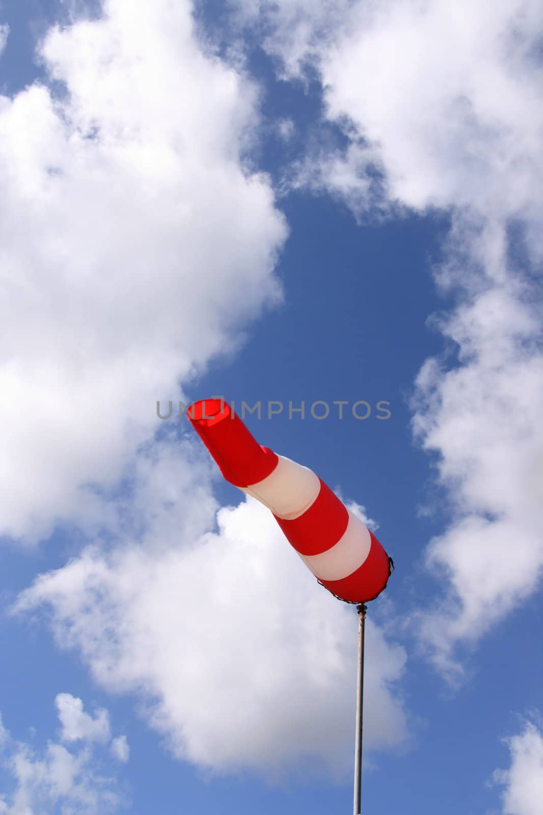 Red and white windsock blows against a blue sky