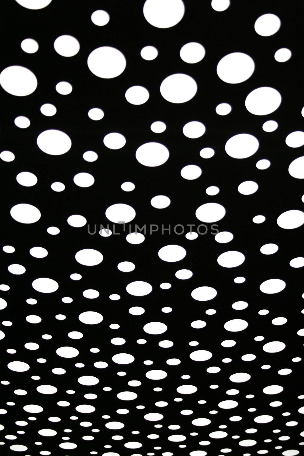 Circle holes in the backlit ceiling of an elevator's cabin. Suited as background pattern.