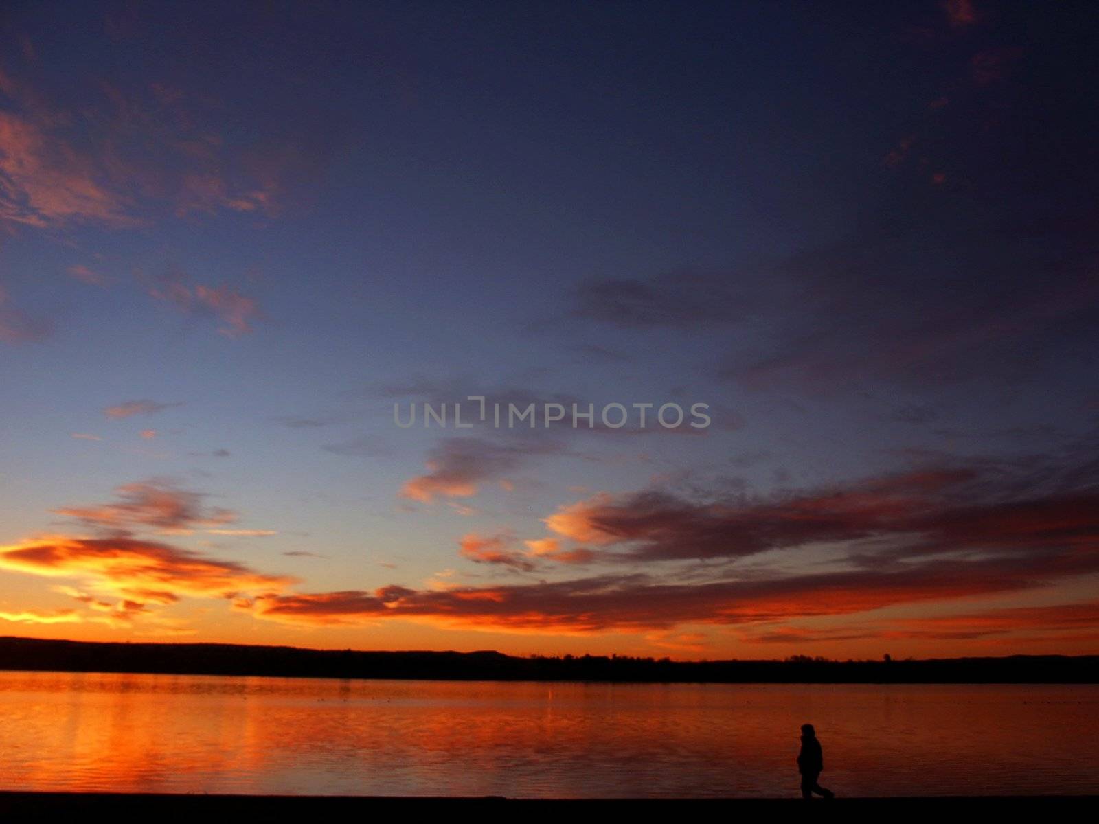 Sunrise on a lake with a person walking by jdebordphoto