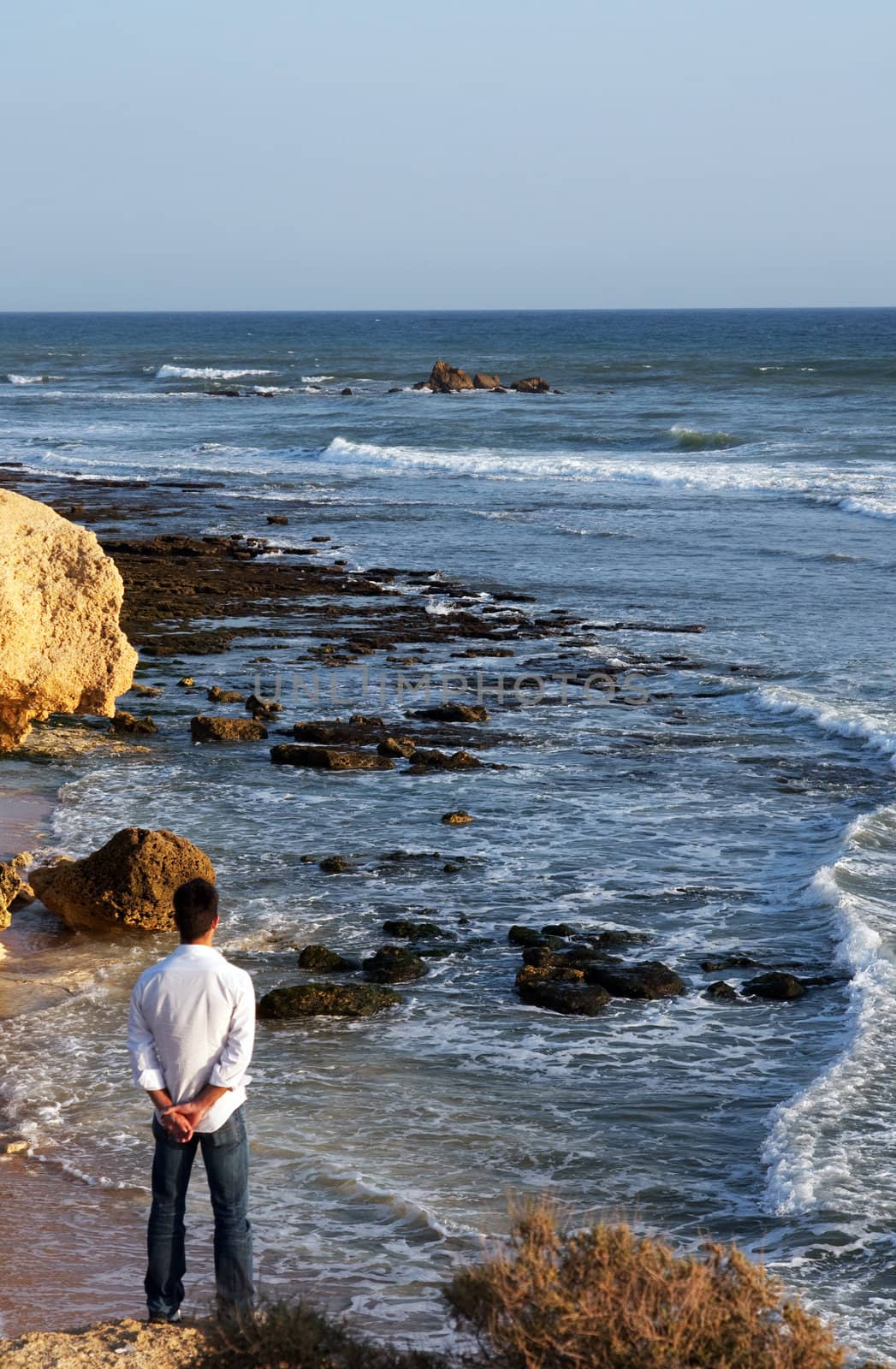 View of a man on the lower left corner gazing the amazing shoreline.