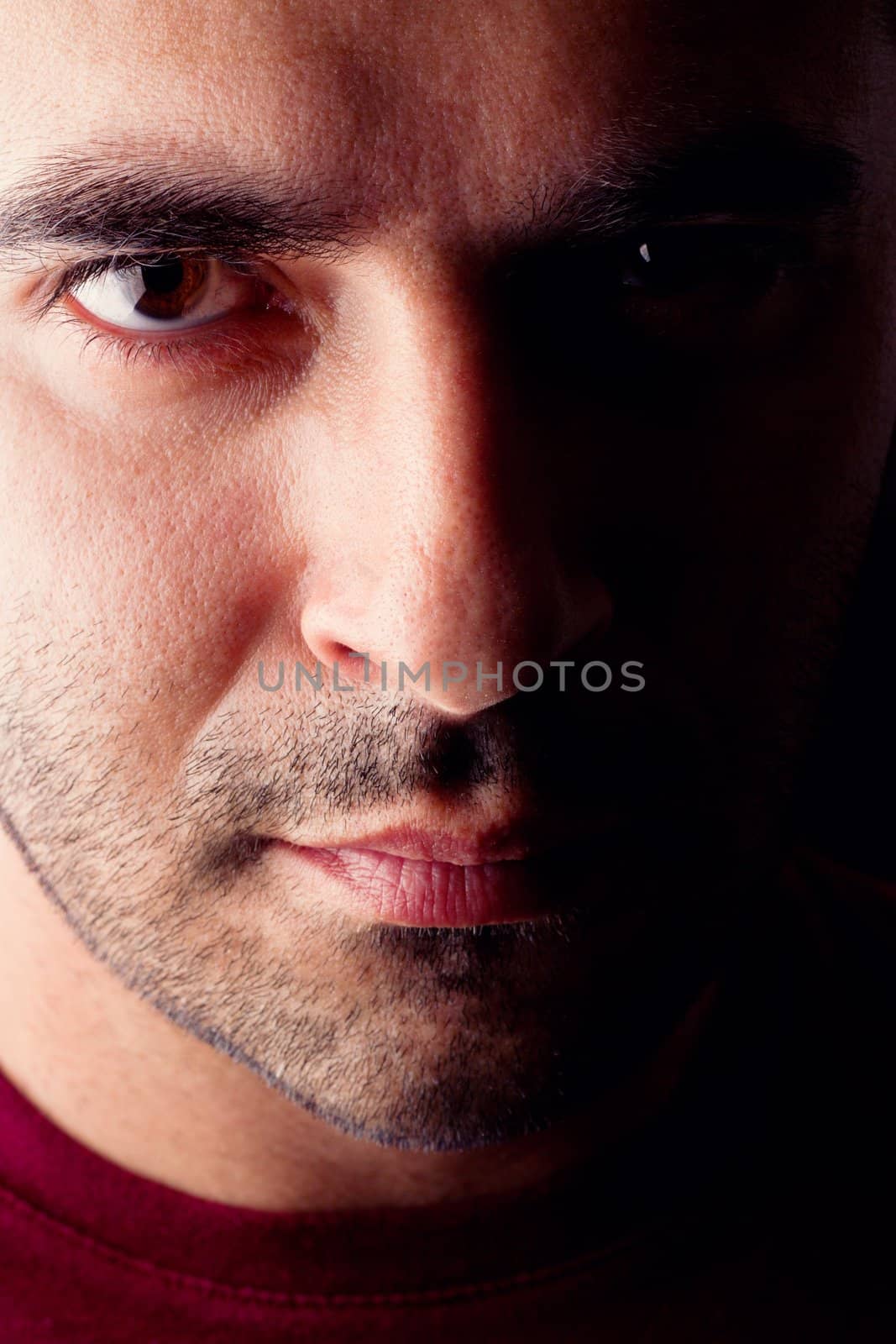 Close detail view of a young male man with a serious look isolated on a black background.