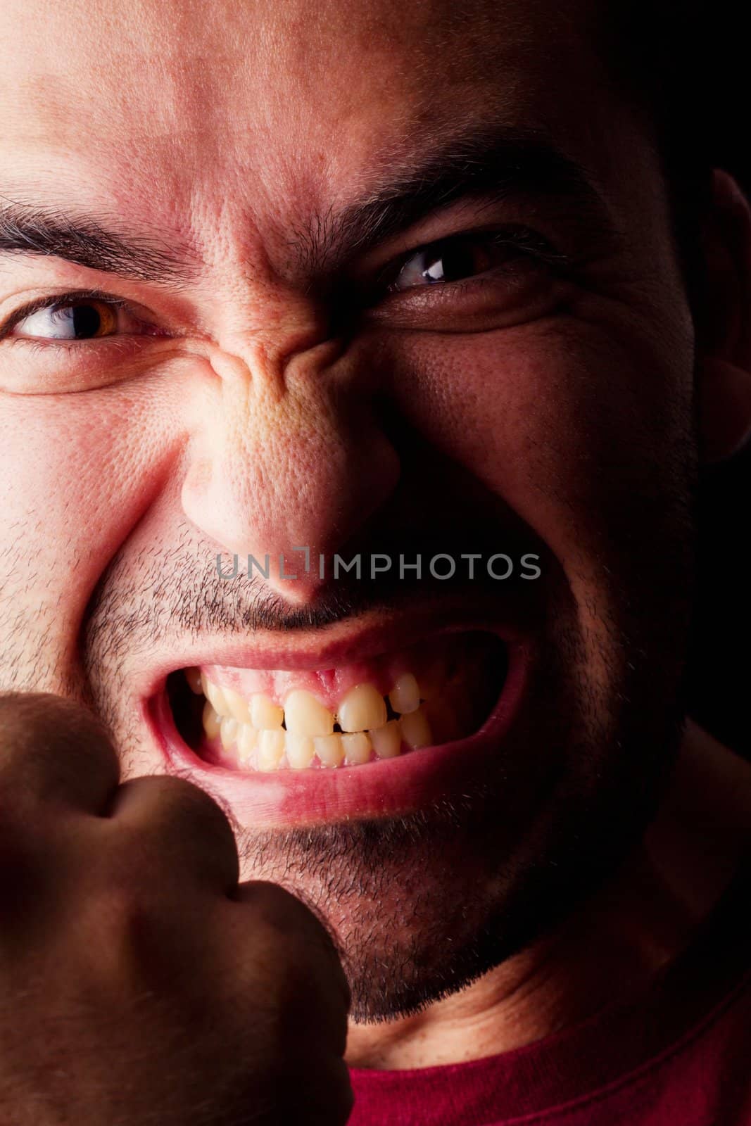 Close detail view of a angry young male man isolated on a black background.