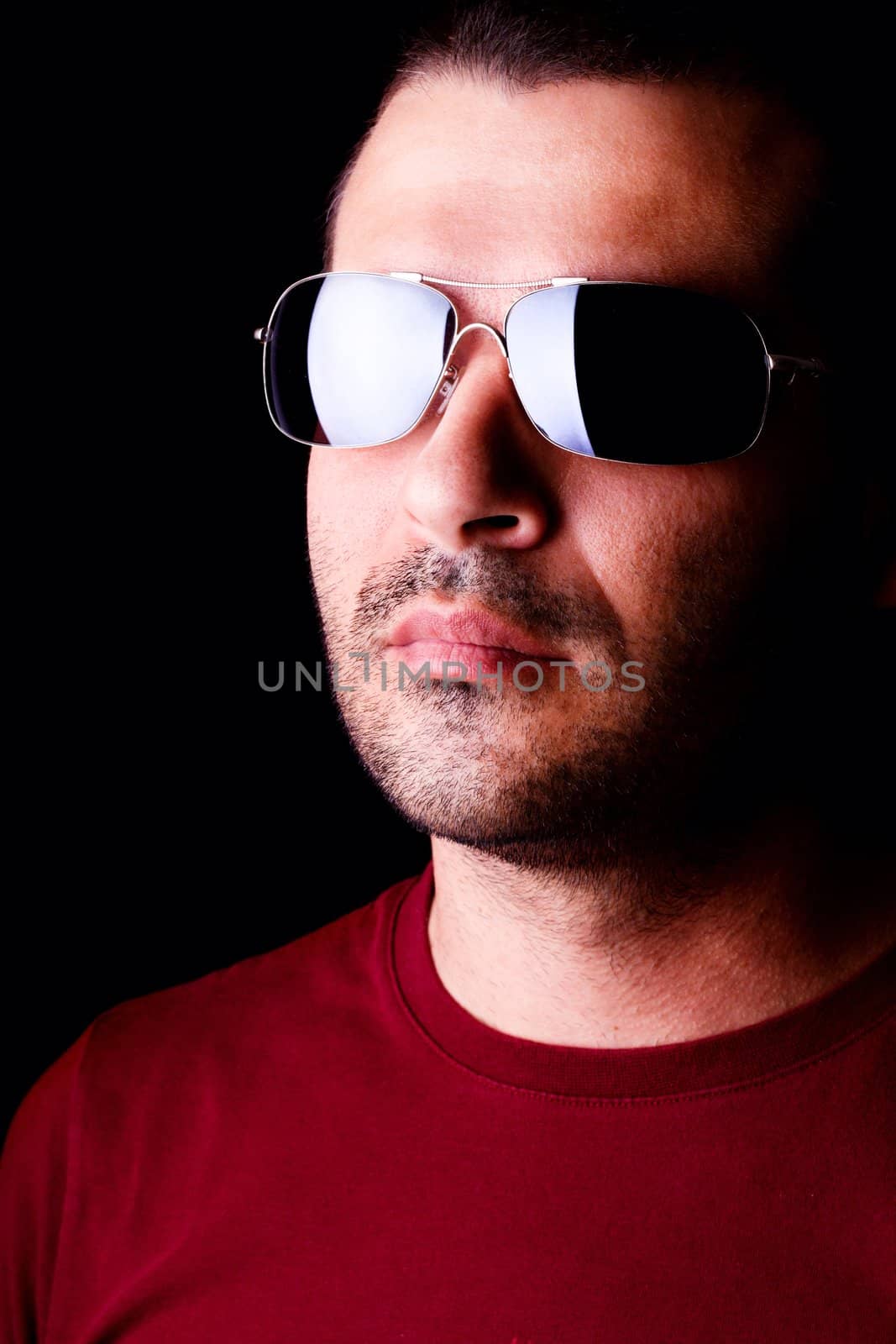 Close detail view of a young male man with dark shades  isolated on a black background.