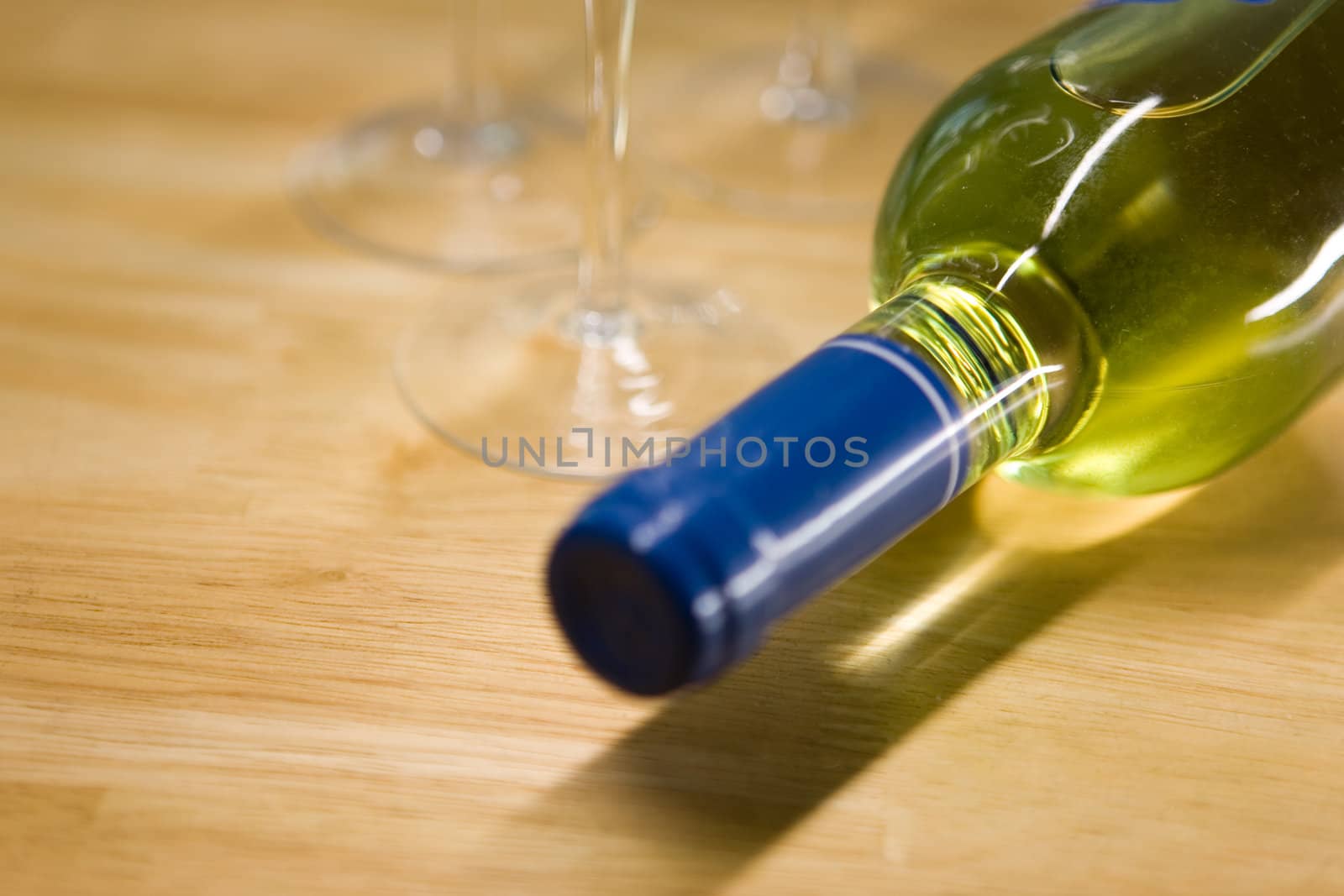 Unopened wine bottle and glasses on a wooden table