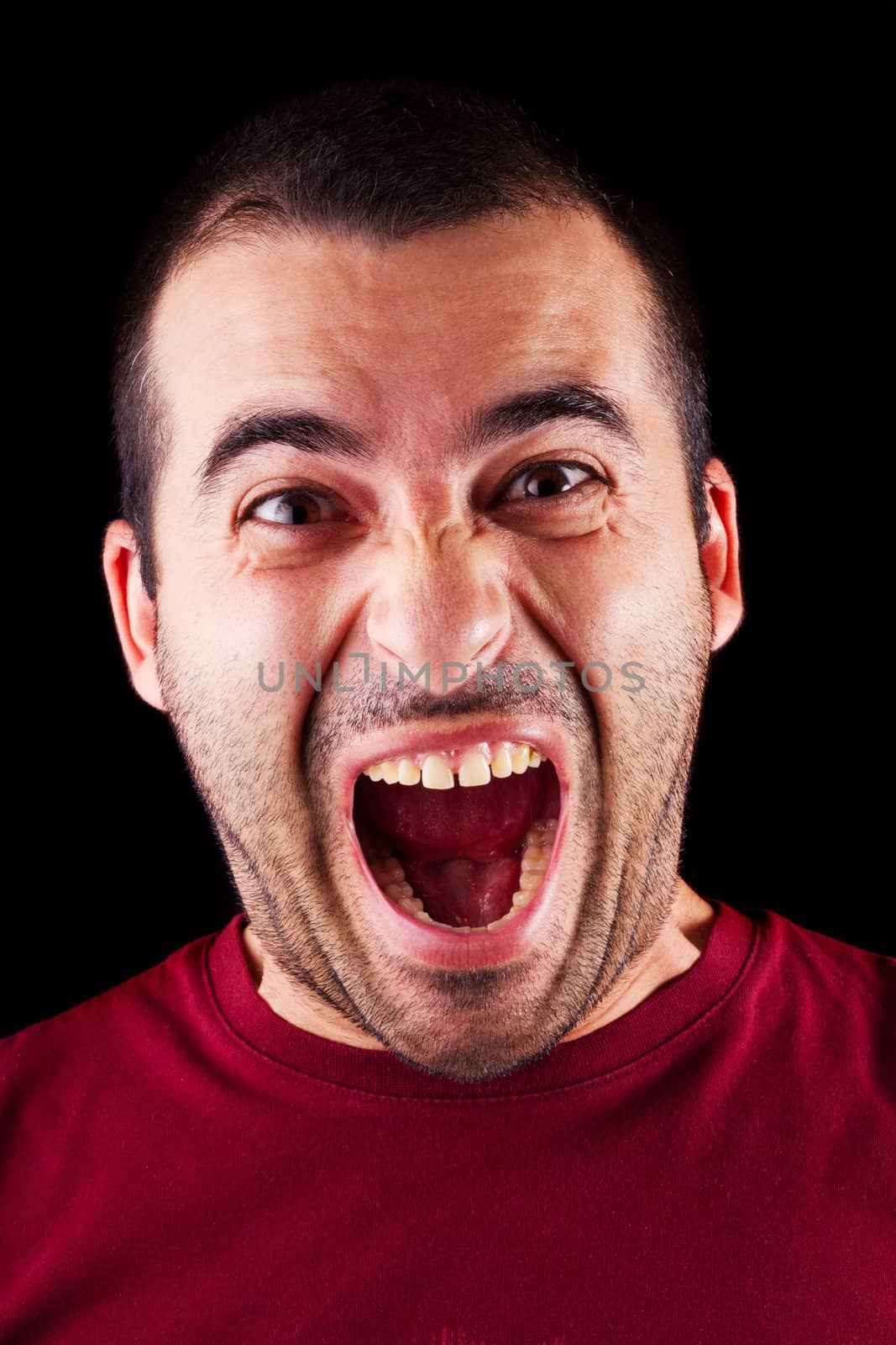 Close detail view of a screaming young male man isolated on a black background.