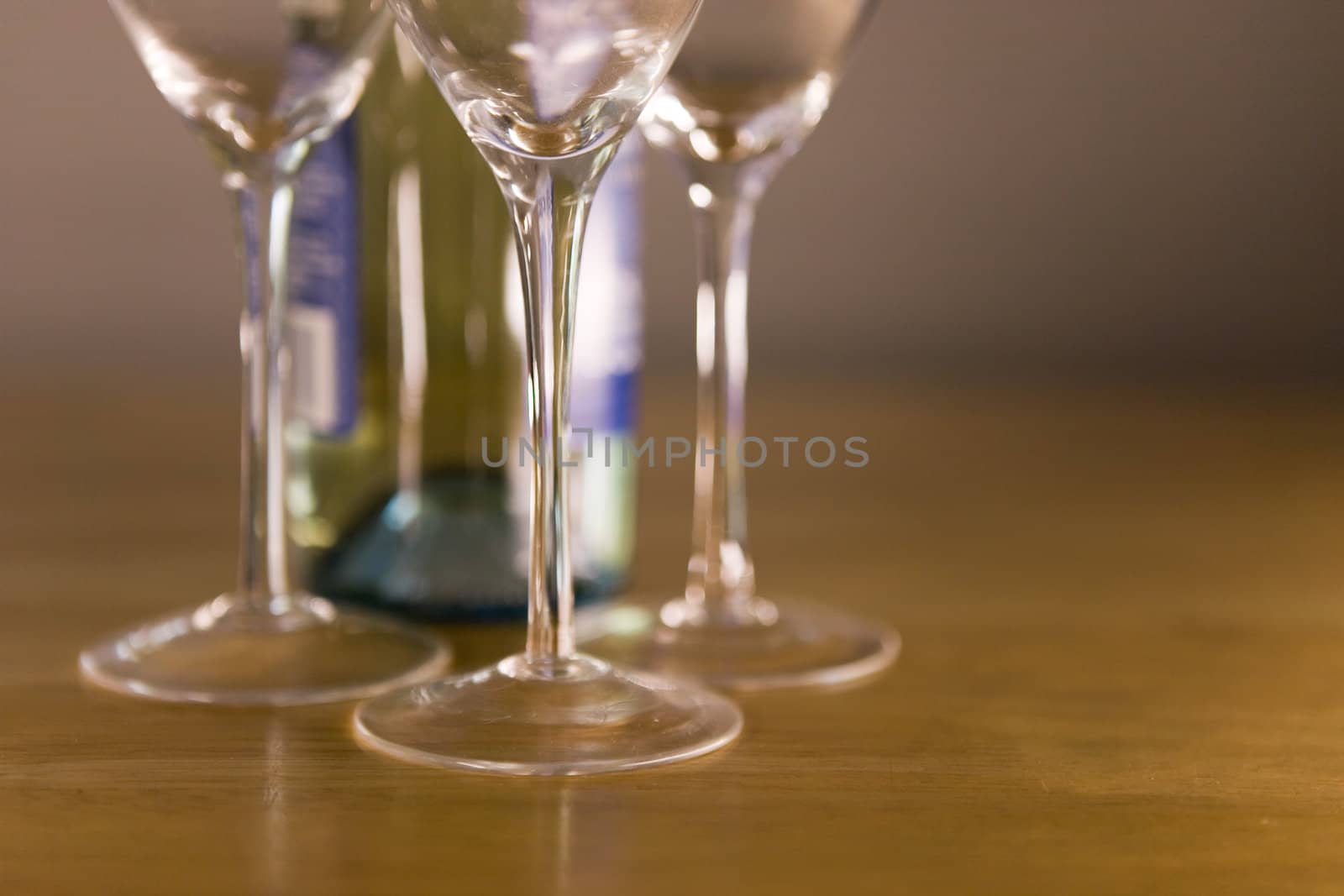 Three empty wine glasses and a bottle on a wooden table