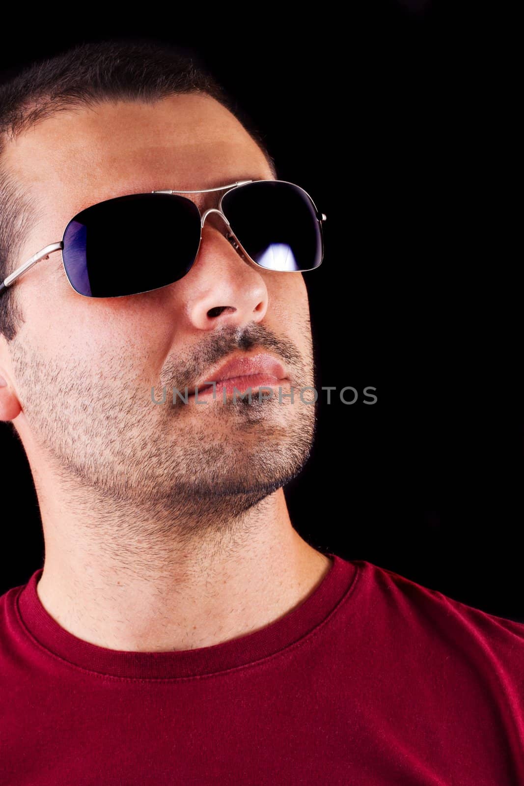 Close detail view of a young male man with dark shades isolated on a black background.