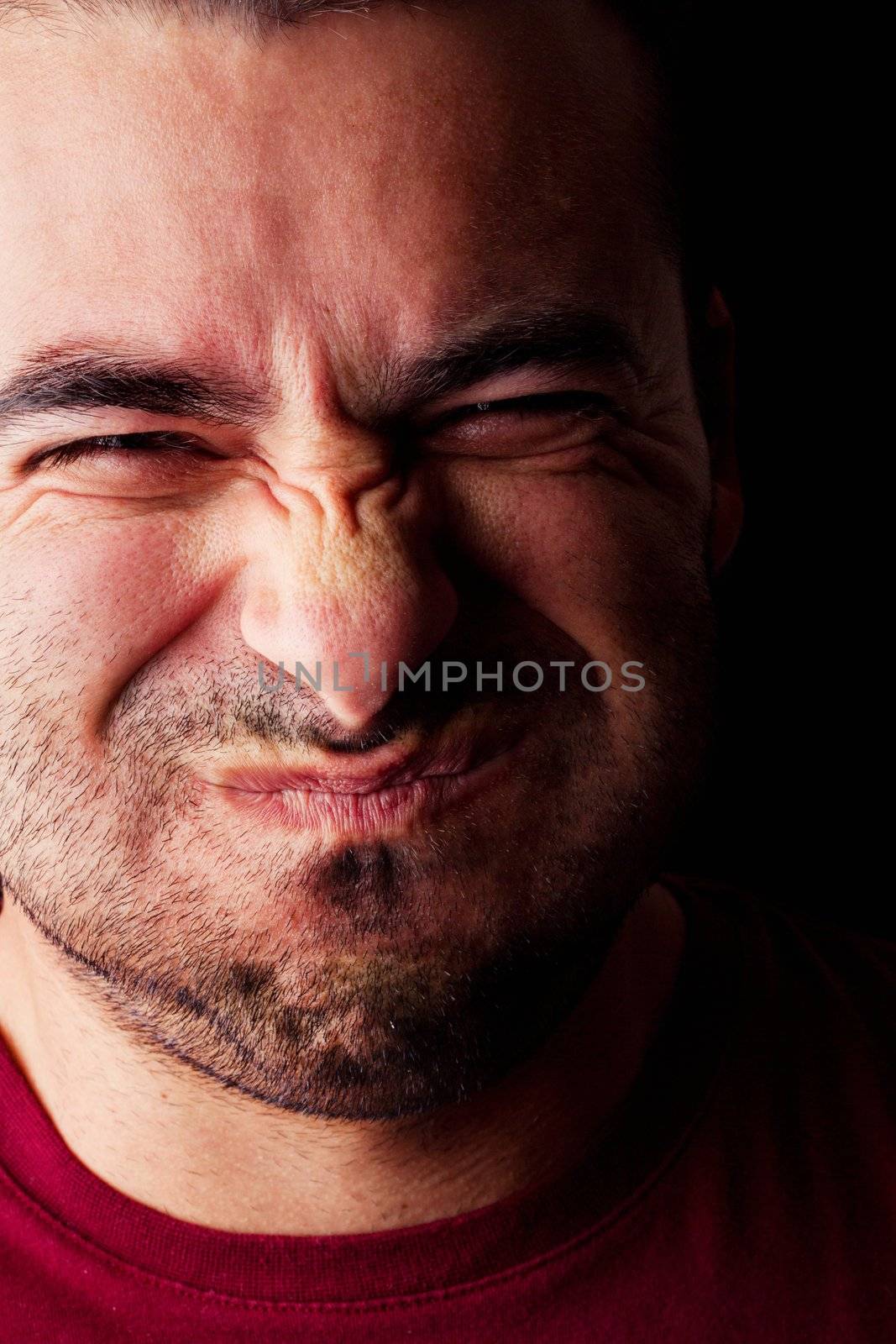 Close detail view of a young male man holding breath isolated on a black background.