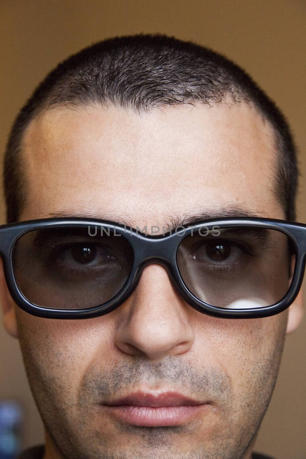 Close view of the face of a man with dark thick glasses.