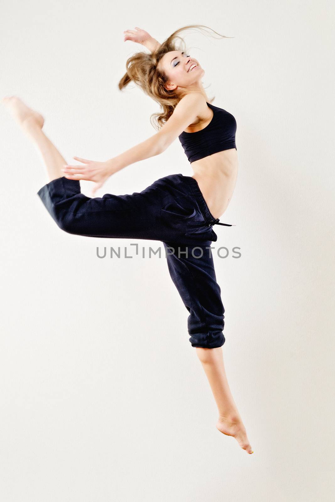 Young woman in tracksuit jumping on white background