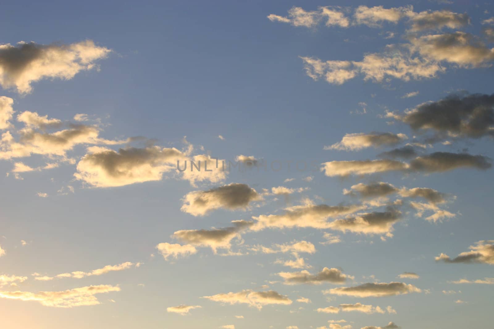 Sun in left corner lighting white wispy clouds from below with a blue sky