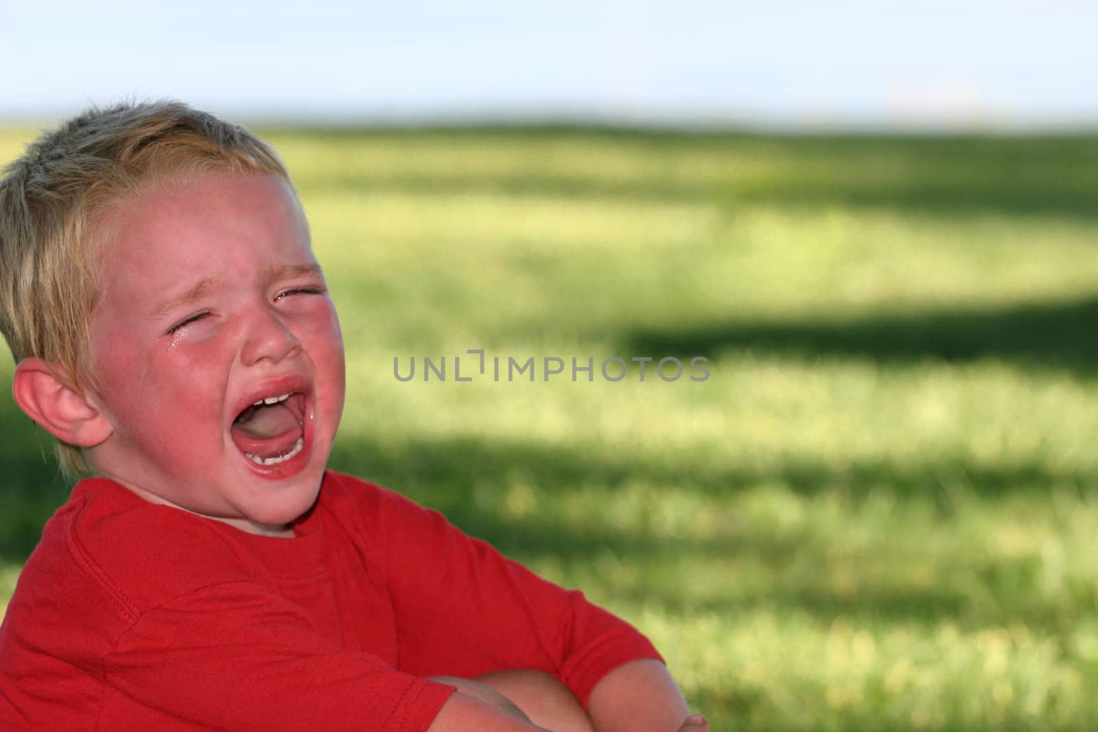 Little boy crying with green grass background