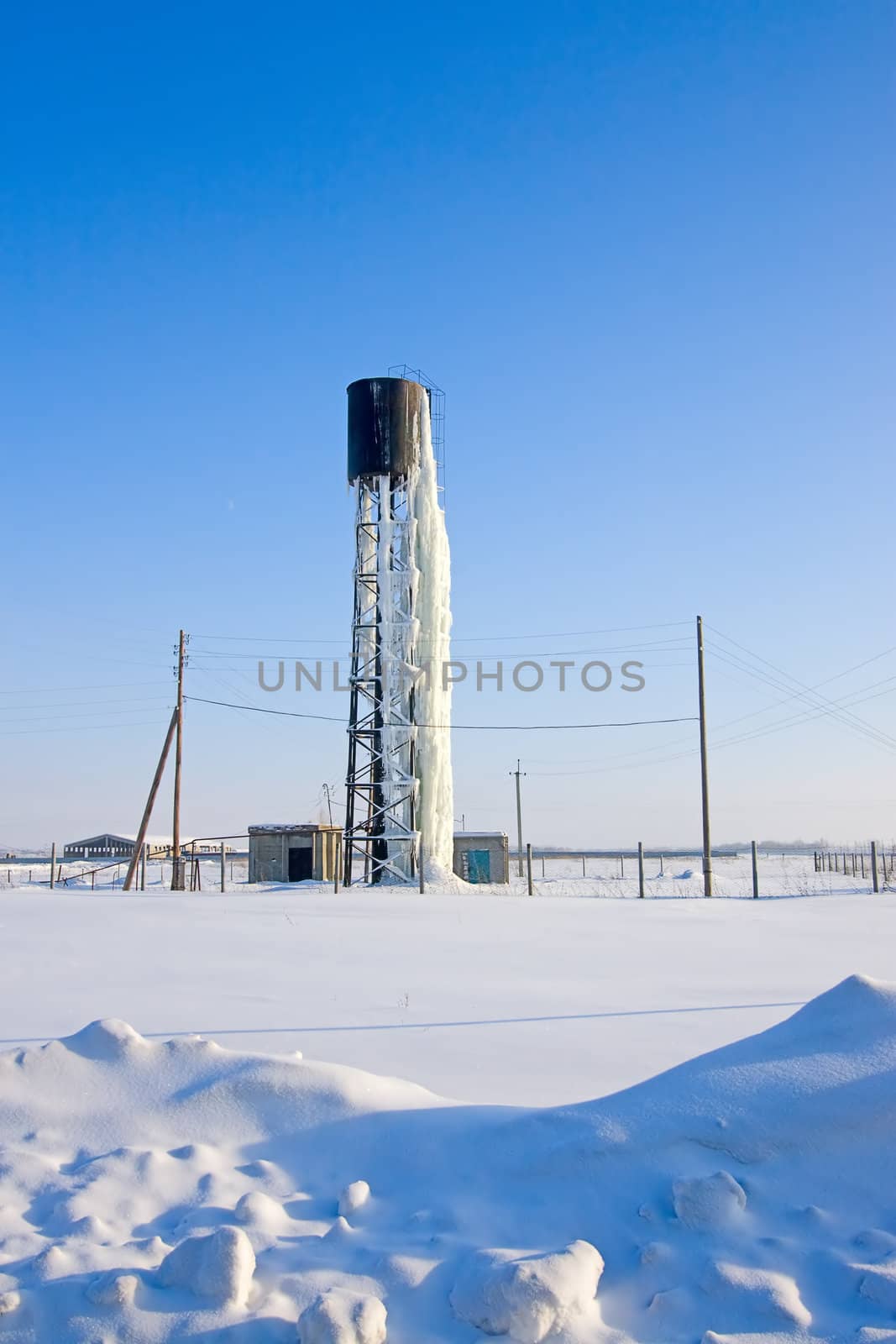 View of  frozen beneath  ice water tower in  winter in  field.
