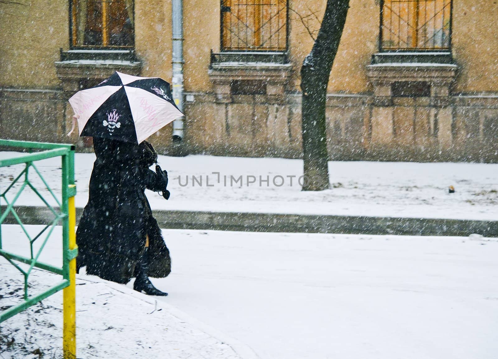 Woman with umbrella in back alley while snowing