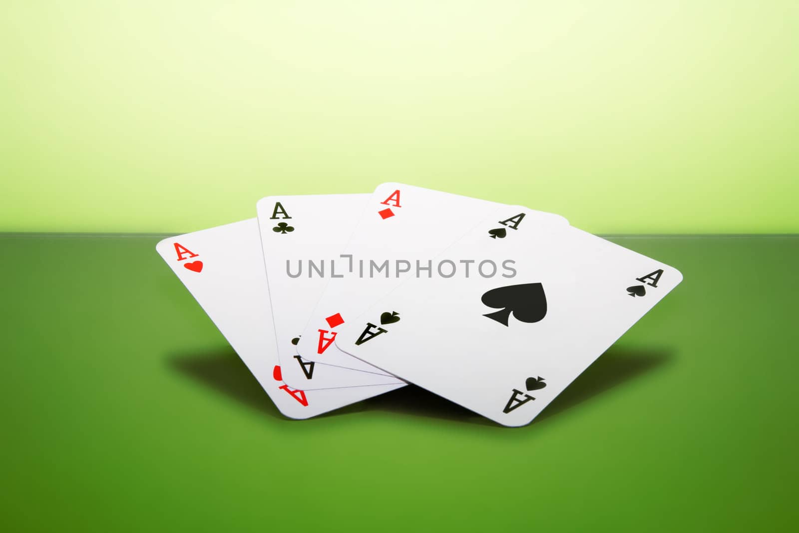 Four playing cards - aces - on a green surface