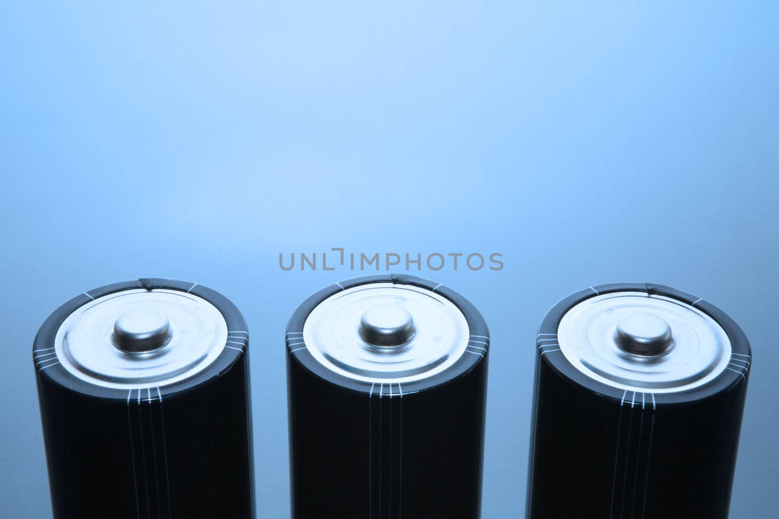 Three LR20 alkaline batteries on a reflective studio background