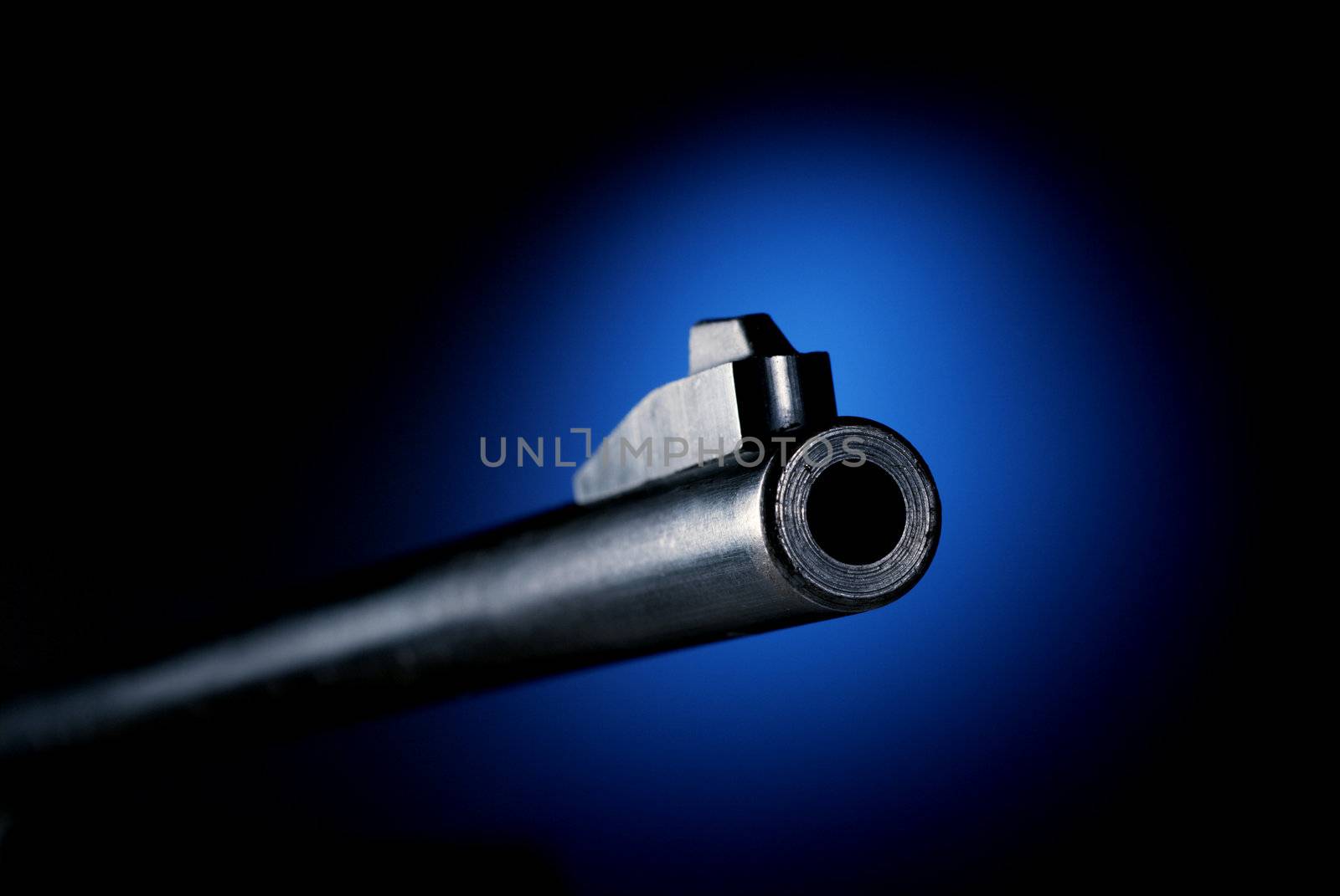 Gun barrel on black background at angle back lit by blue spot