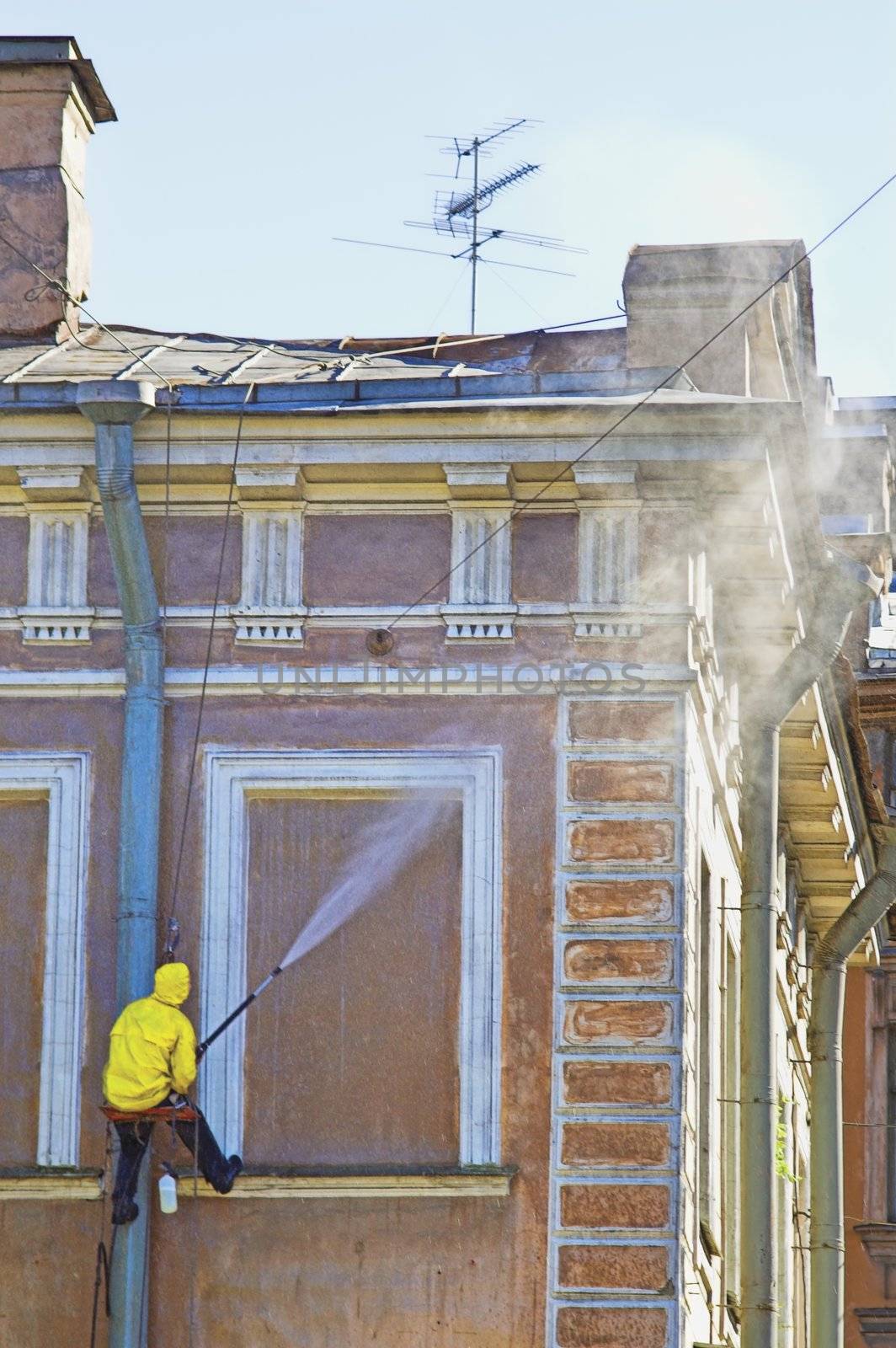 Cleaning service worker washing old building facade