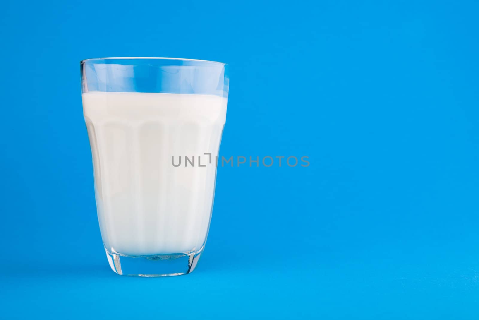 Milk in glass over blue background