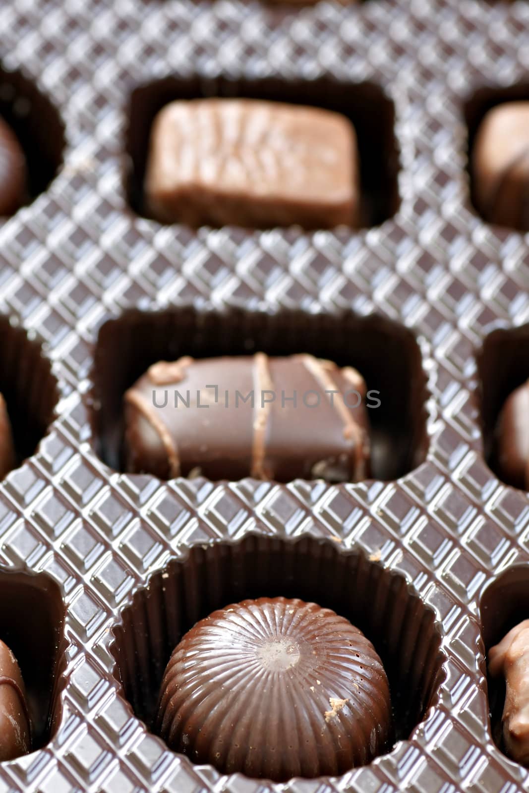 Inside a box of chocolates, row of three, differents shapes and taste.