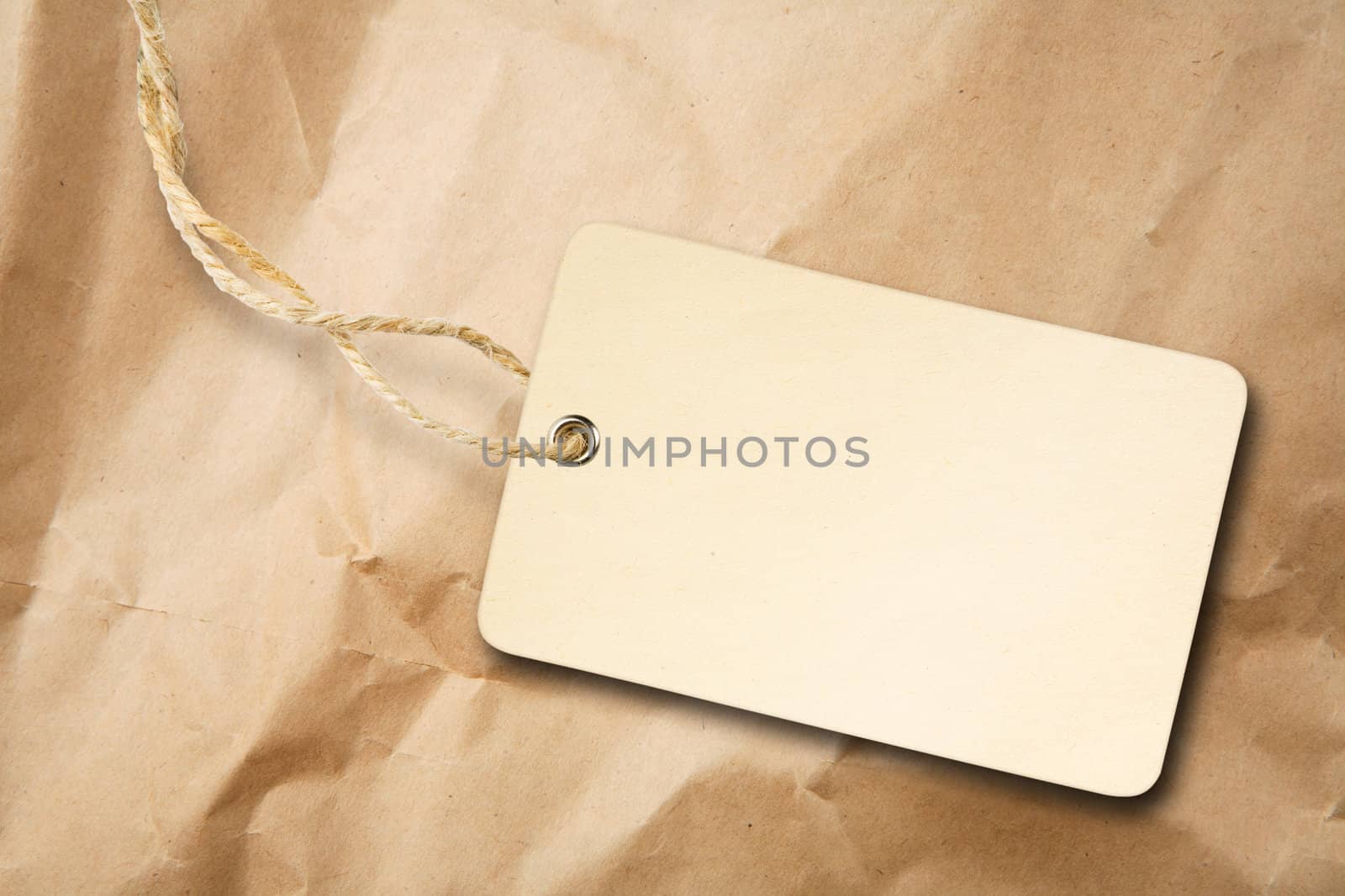 Blank packaging label with cotton string on crumpled brown paper