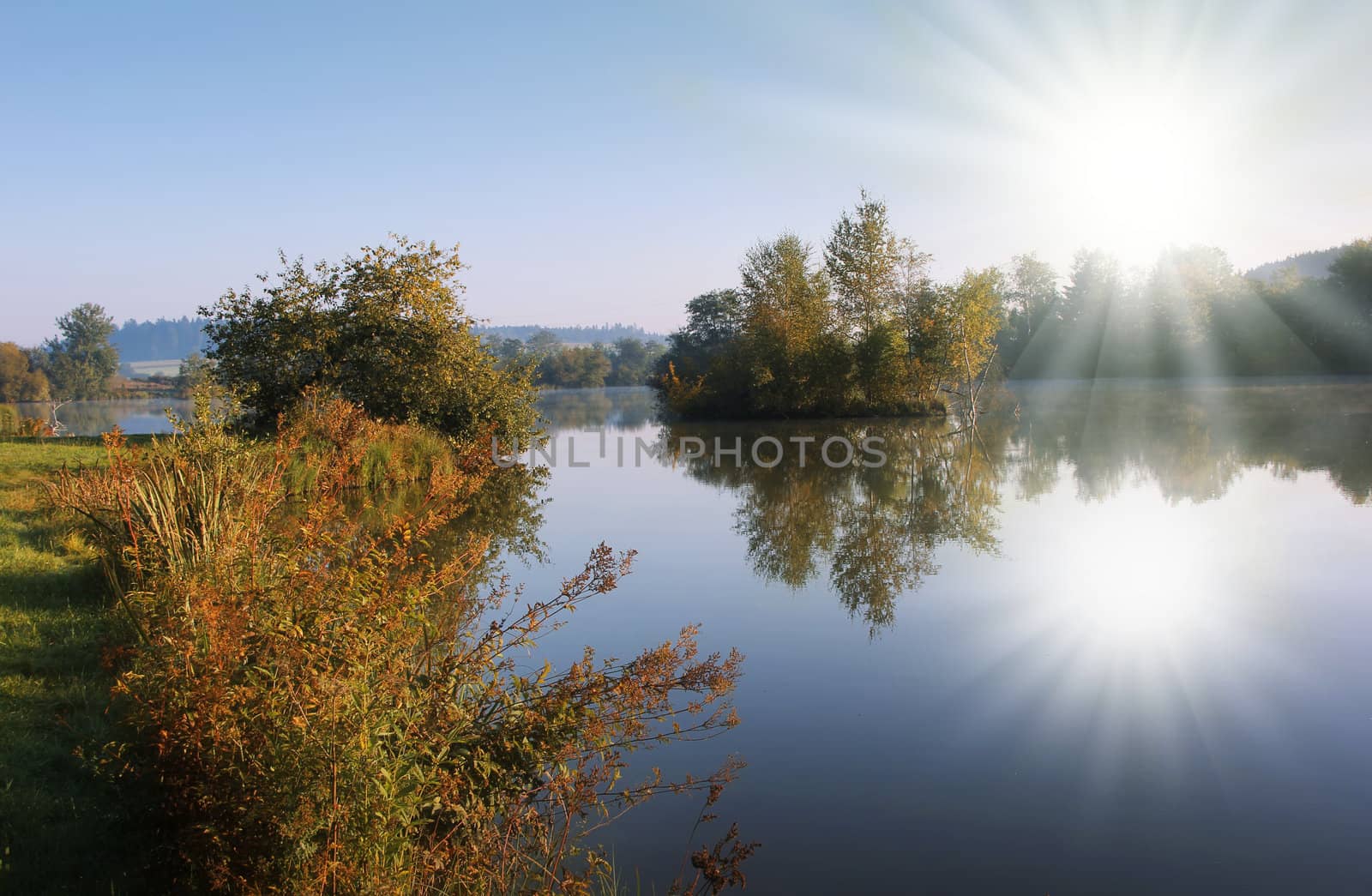 blue lake with sunbeam and isle in the autumn