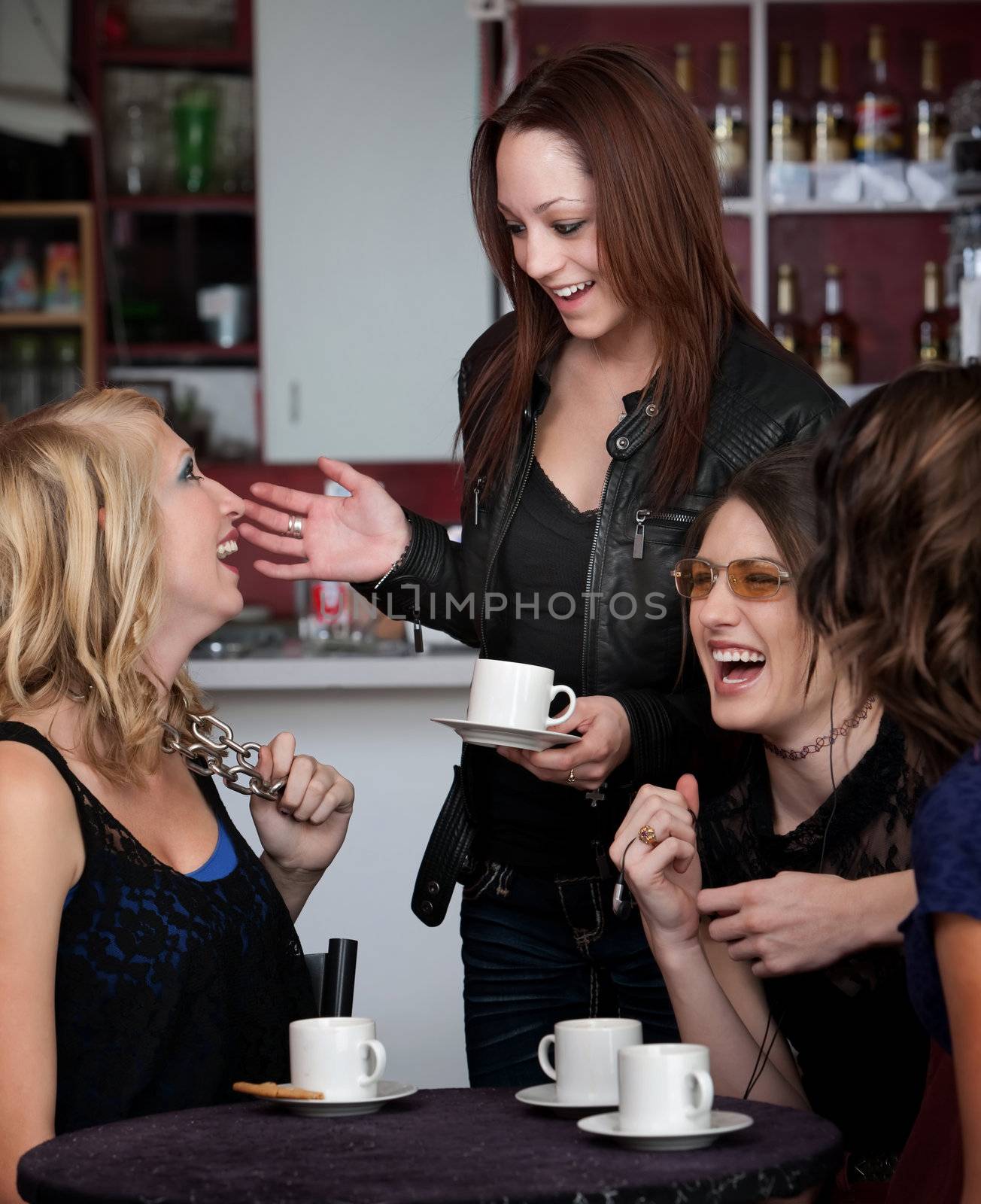 Foursome of young cute teen friends laughing at a cafe