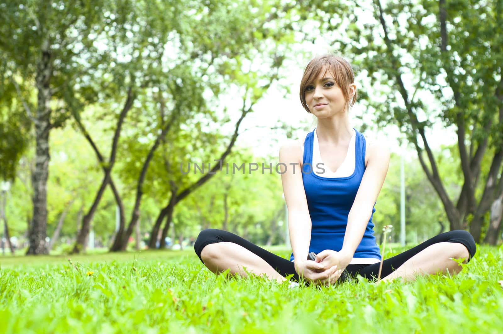 young woman is engaged in yoga, in summer forest on a green grass