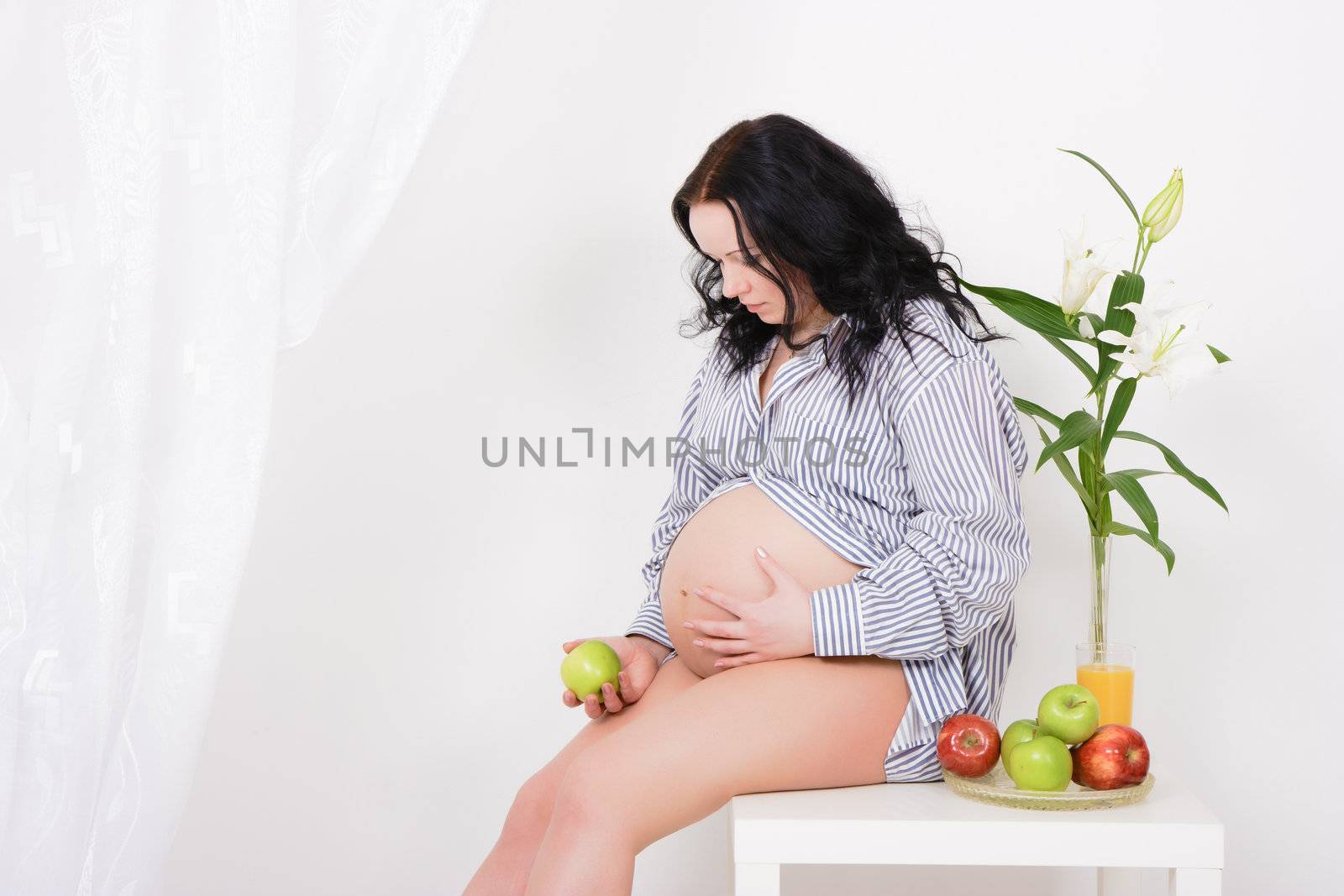pregnant girl, apples and lilies. Studio photography
