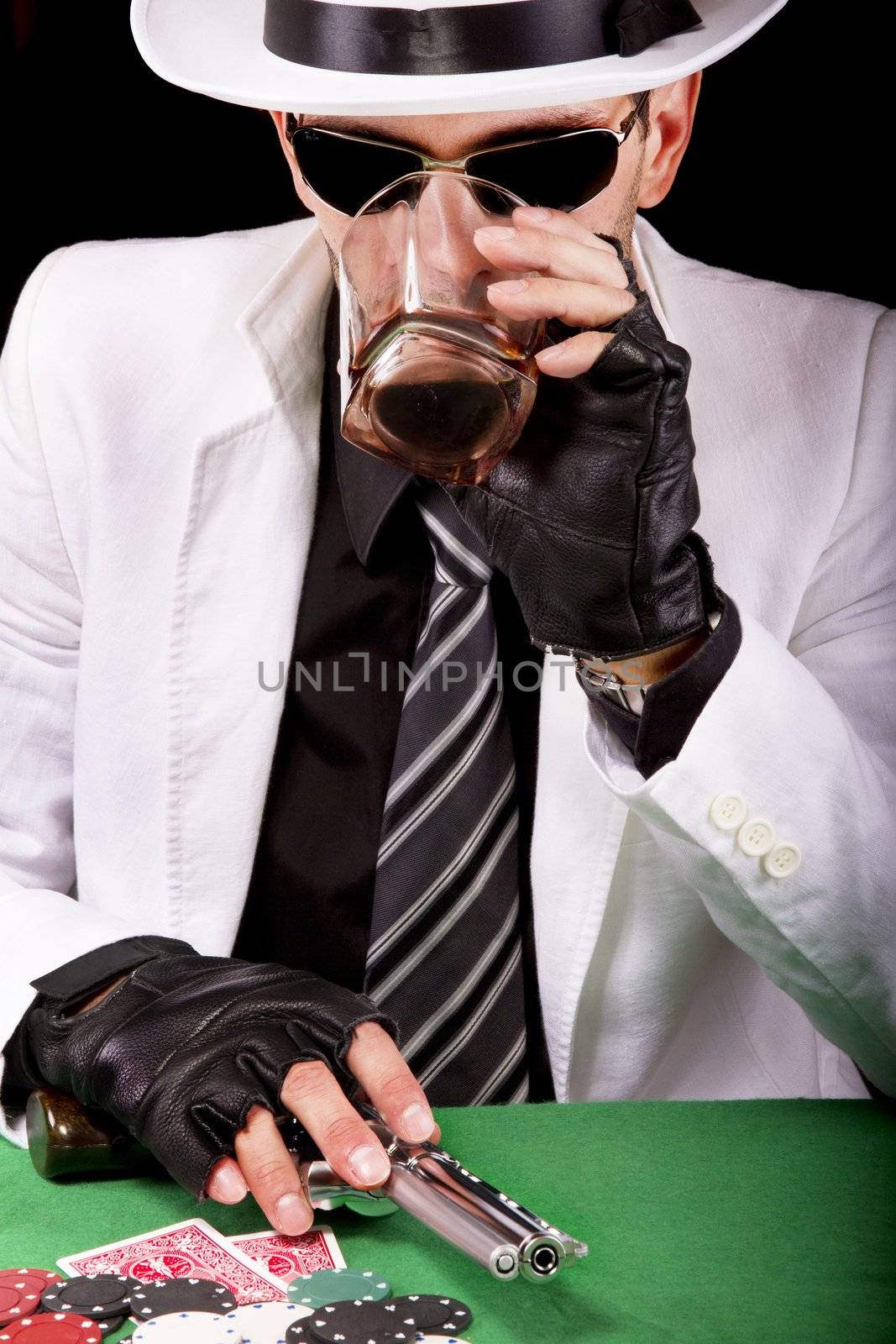 View of a gangster man playing some cards and poker, having a drink.