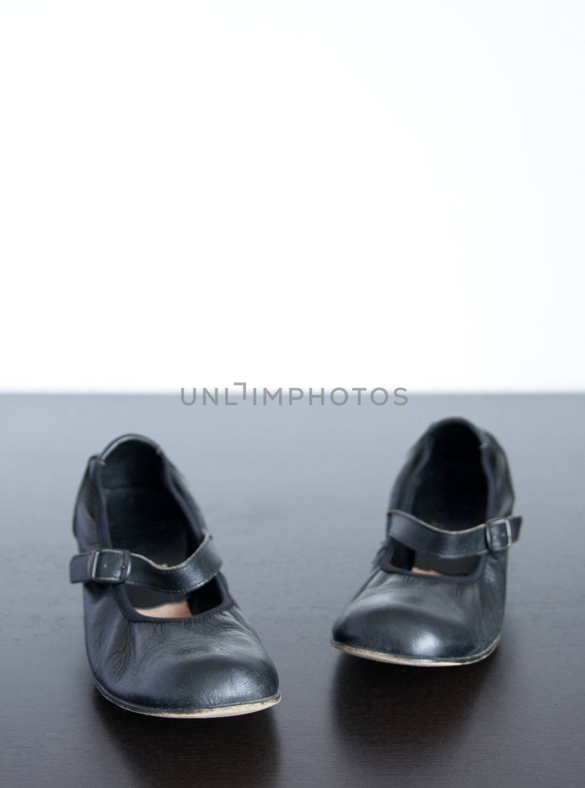 Black shoes on wooden surface, wish copy-space behind.