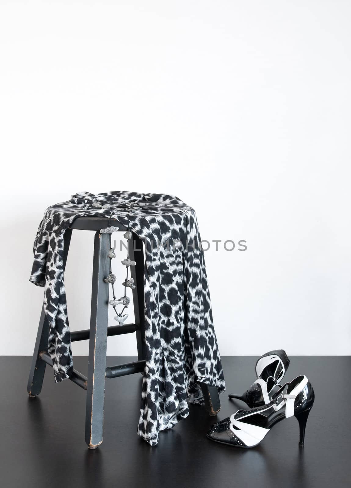 Black and white shoes and fashionable dress on old wooden stool.