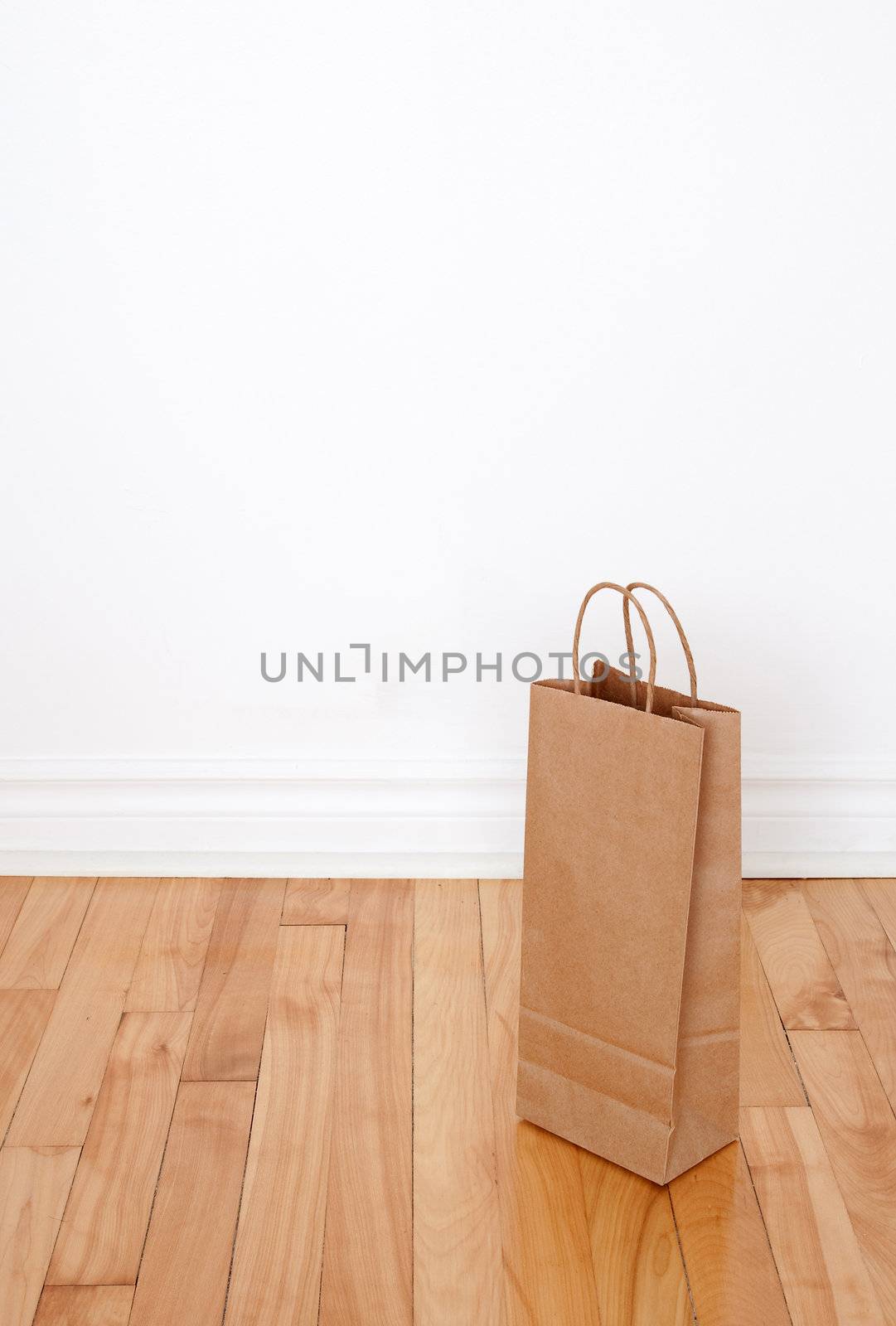 Paper bag on wooden floor against the white wall.