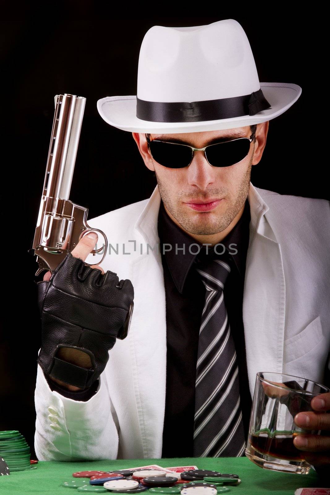 View of a gangster man playing some cards and poker, holding a gun.