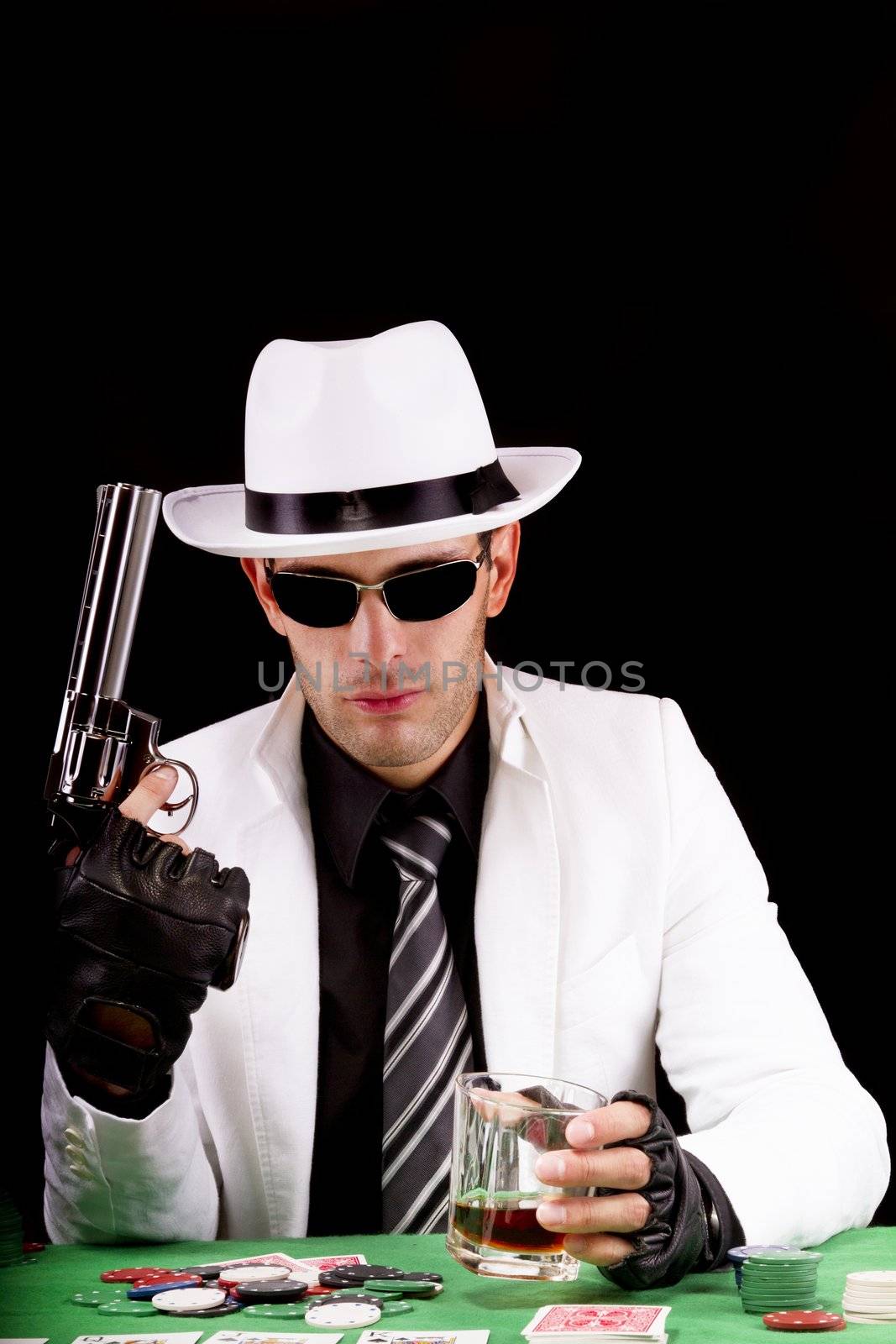 View of a gangster man playing some cards and poker, holding a gun.