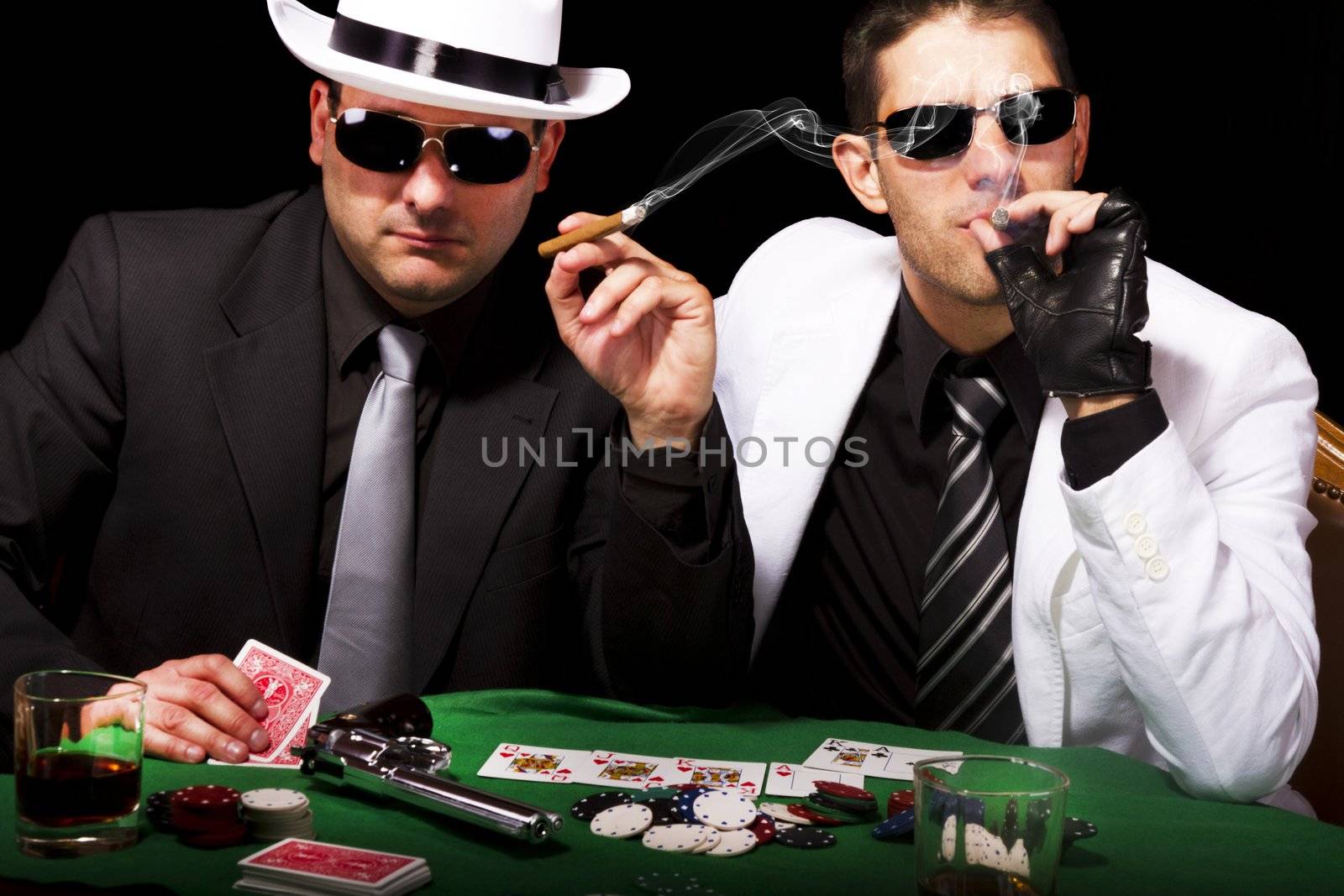 View of two gangster males playing some poker and smoking Cuban cigars.